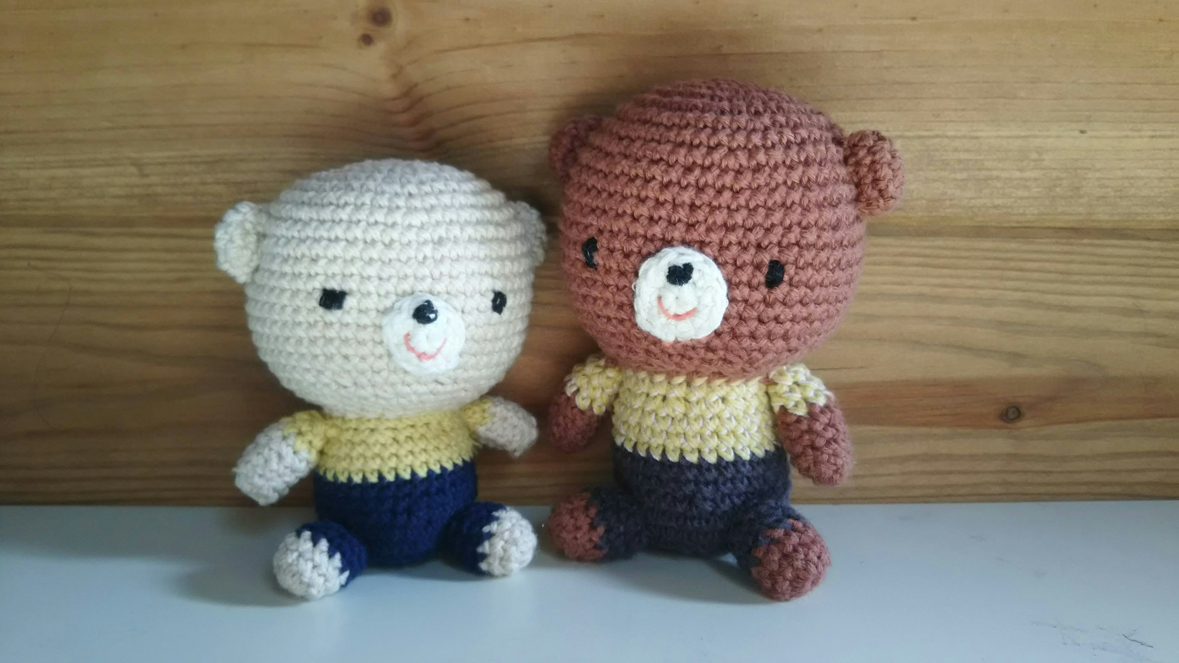 Two crocheted bear dolls in white and brown sitting side by side