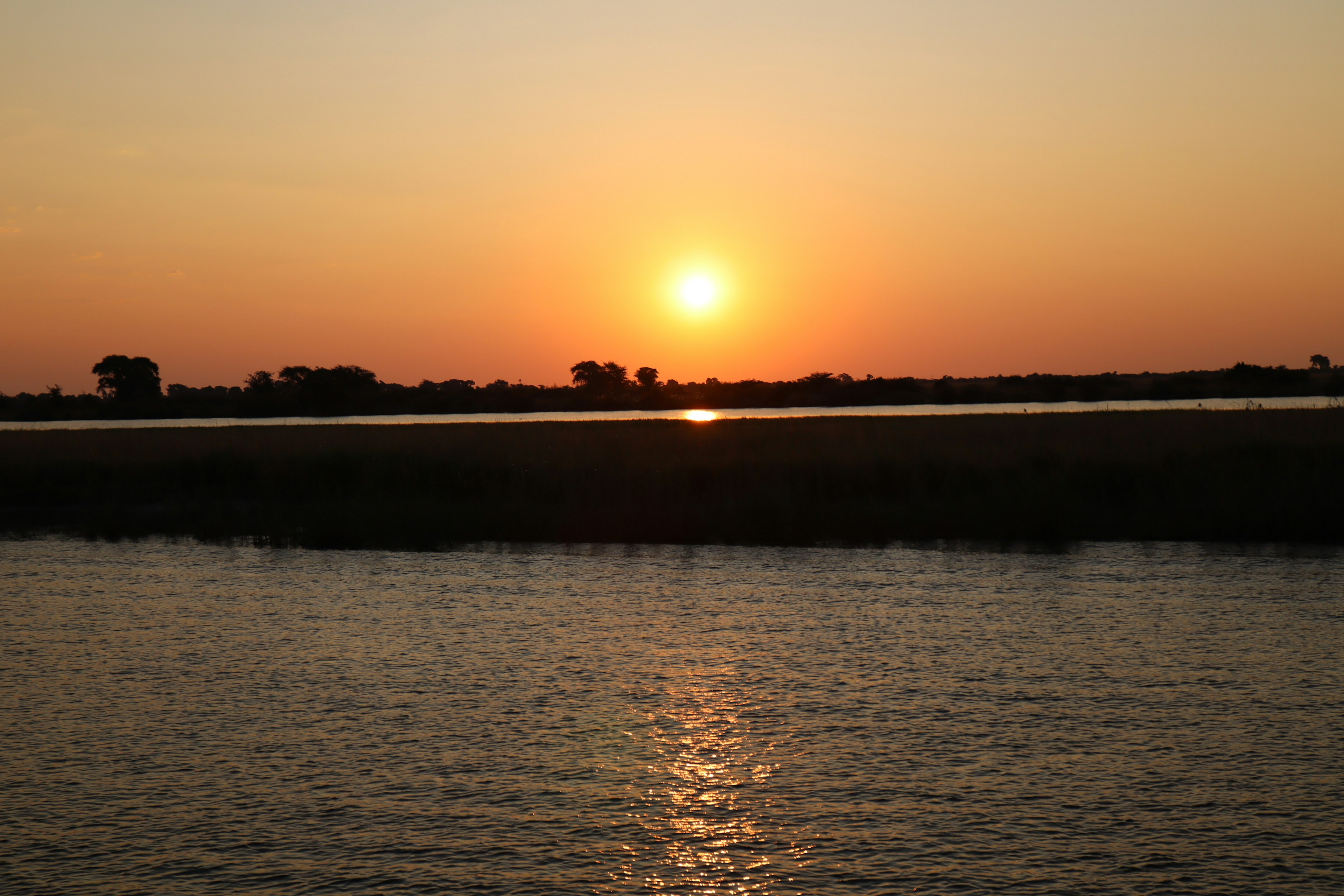 夕日が水面に反射する静かな湖の風景