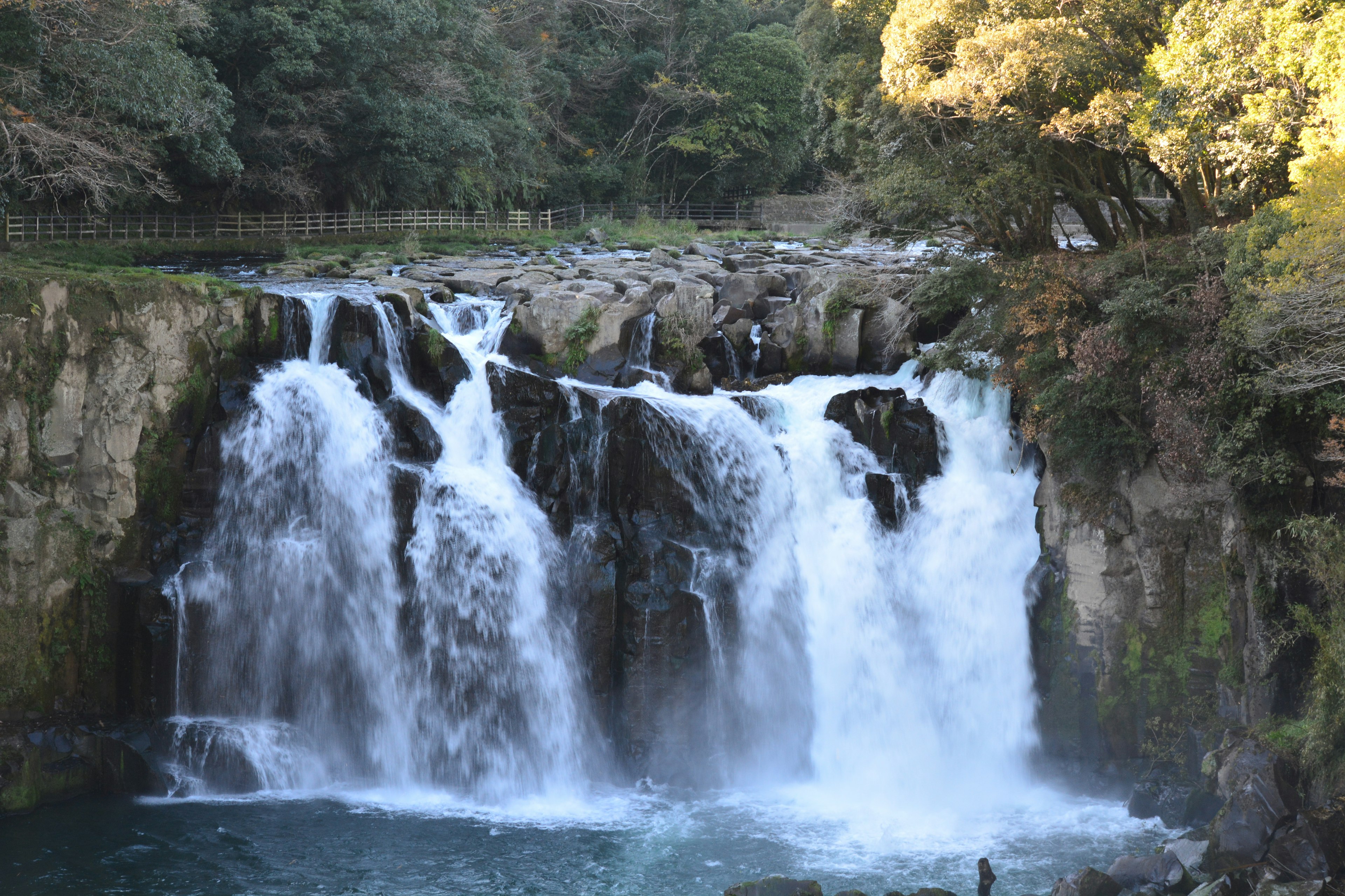 Una bellissima cascata che scorre in un paesaggio sereno circondato da una vegetazione lussureggiante