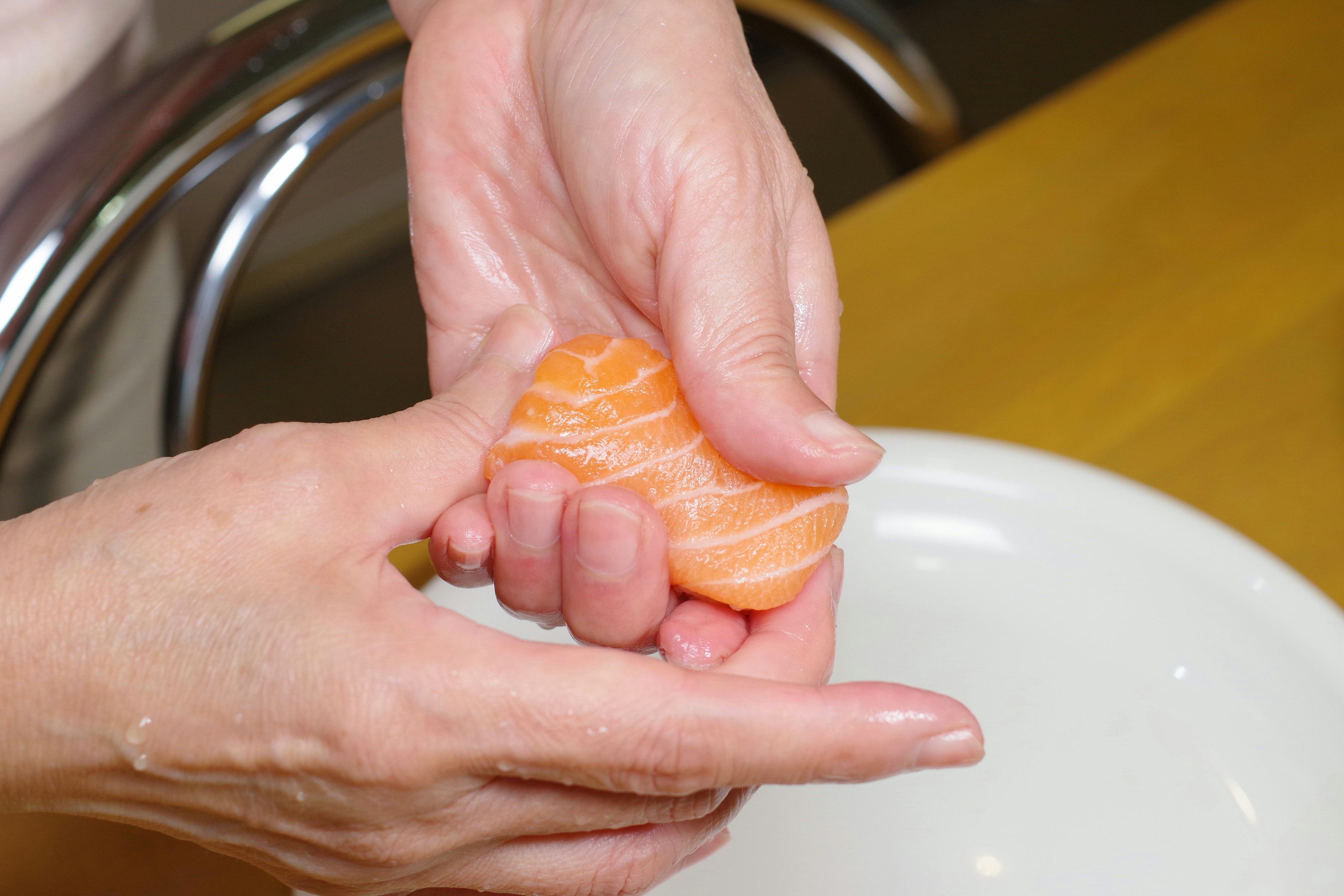 Mani che tengono sashimi di salmone di colore arancione brillante