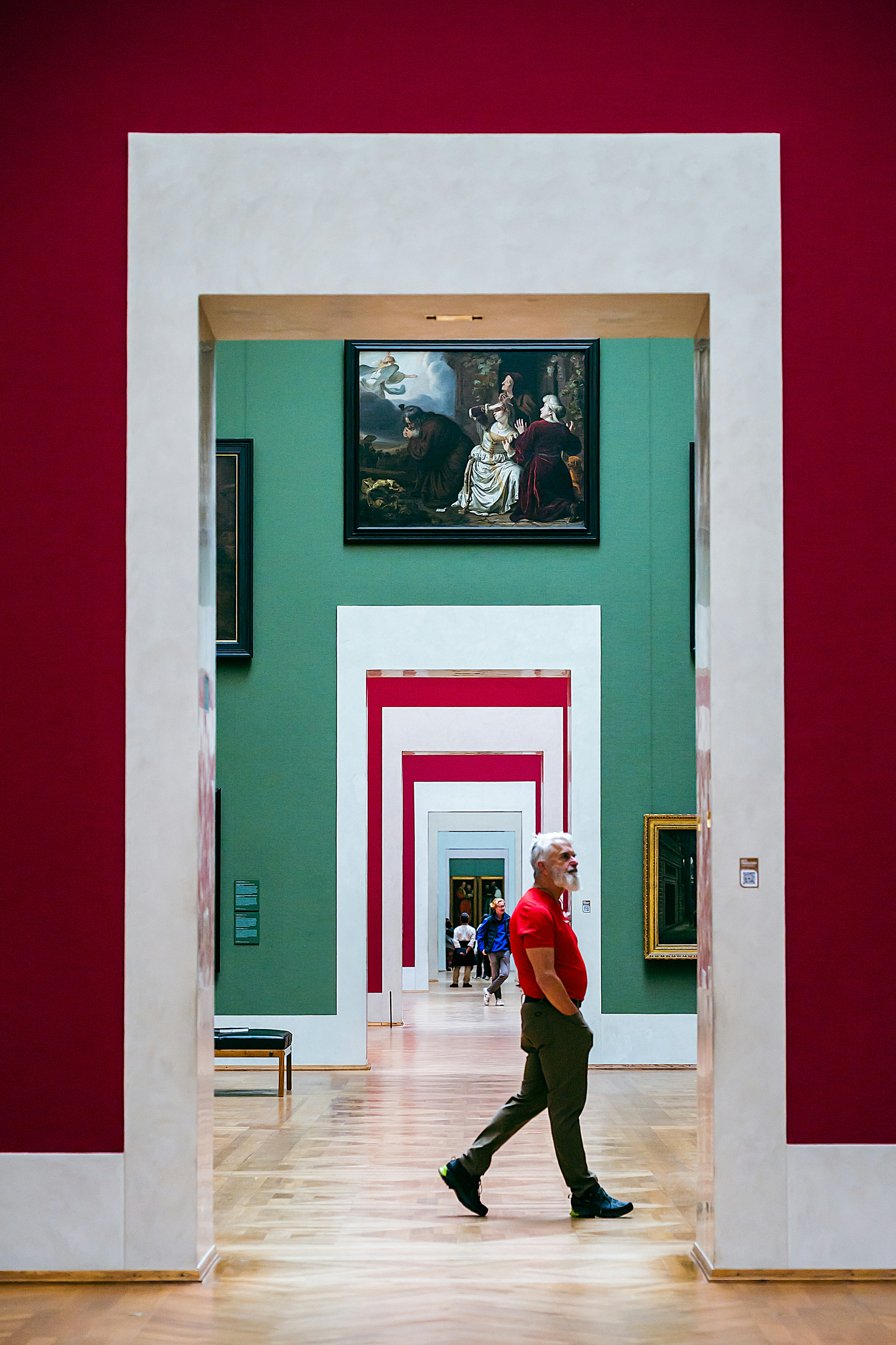 Un uomo che cammina in una galleria d'arte con pareti rosse e verdi