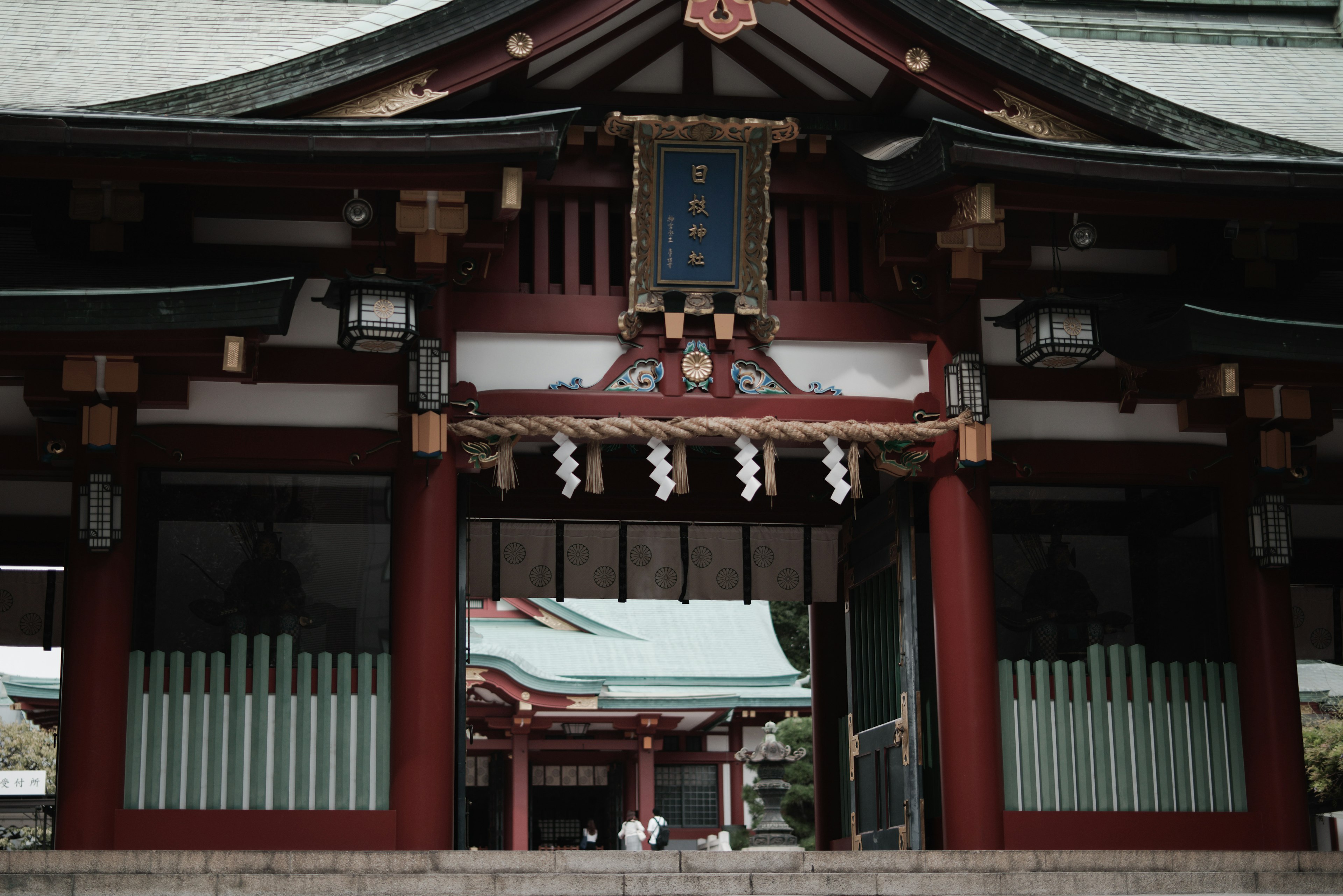 Entrance of a shrine with red pillars and green lattice windows