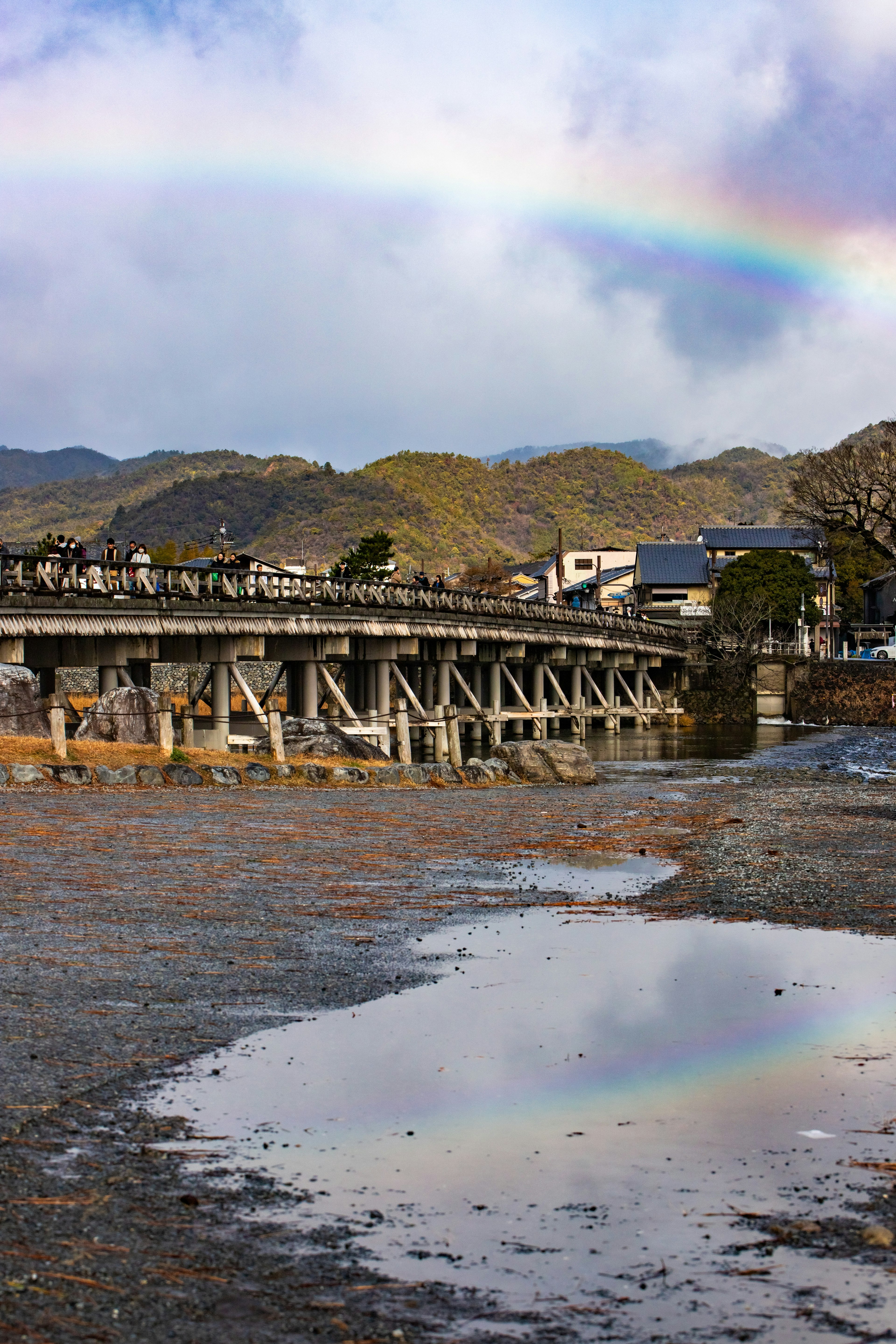 Una vista escénica de un puente bajo un arcoíris con reflejos en un charco