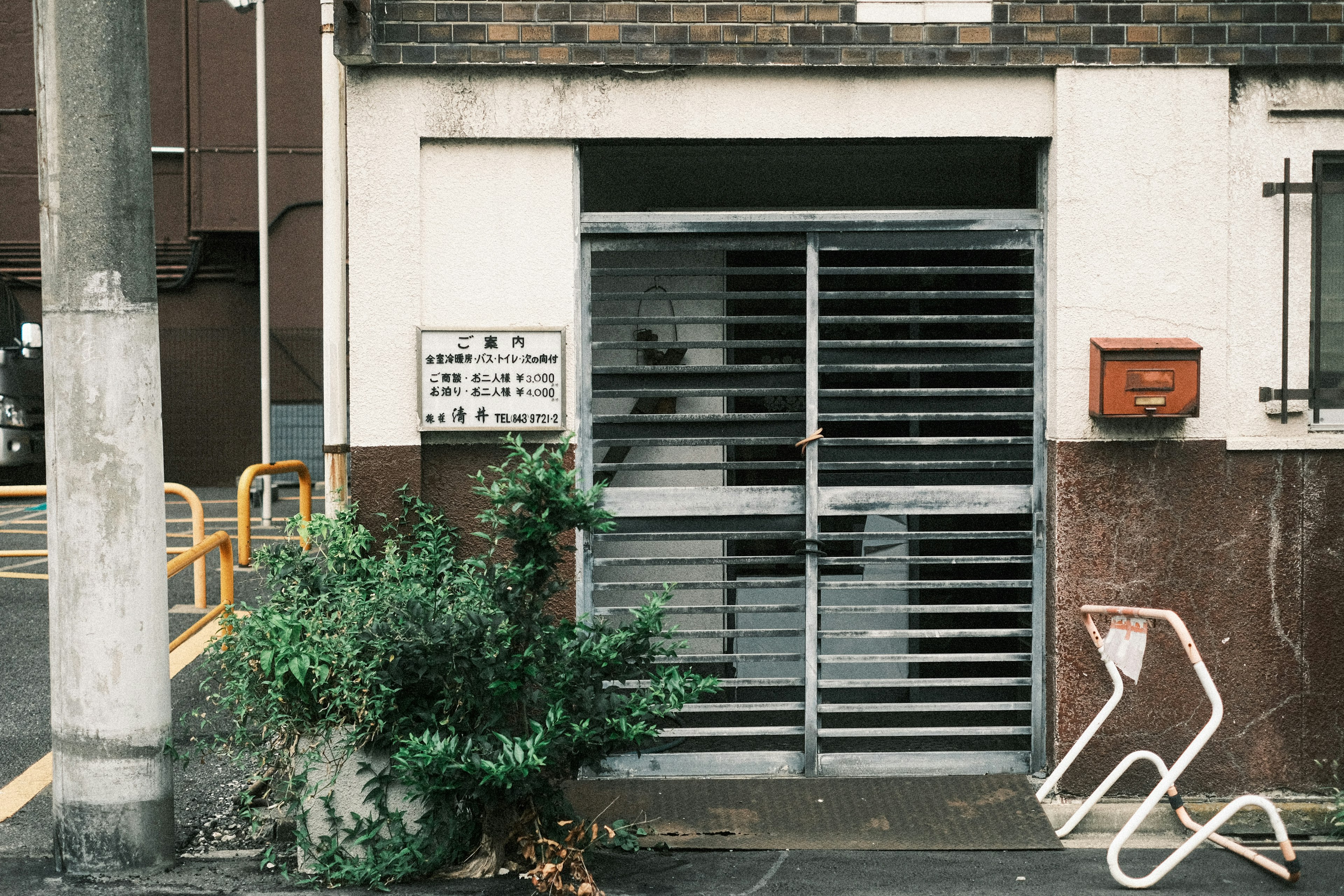 Entrance of an old building featuring a steel slat gate and a small plant