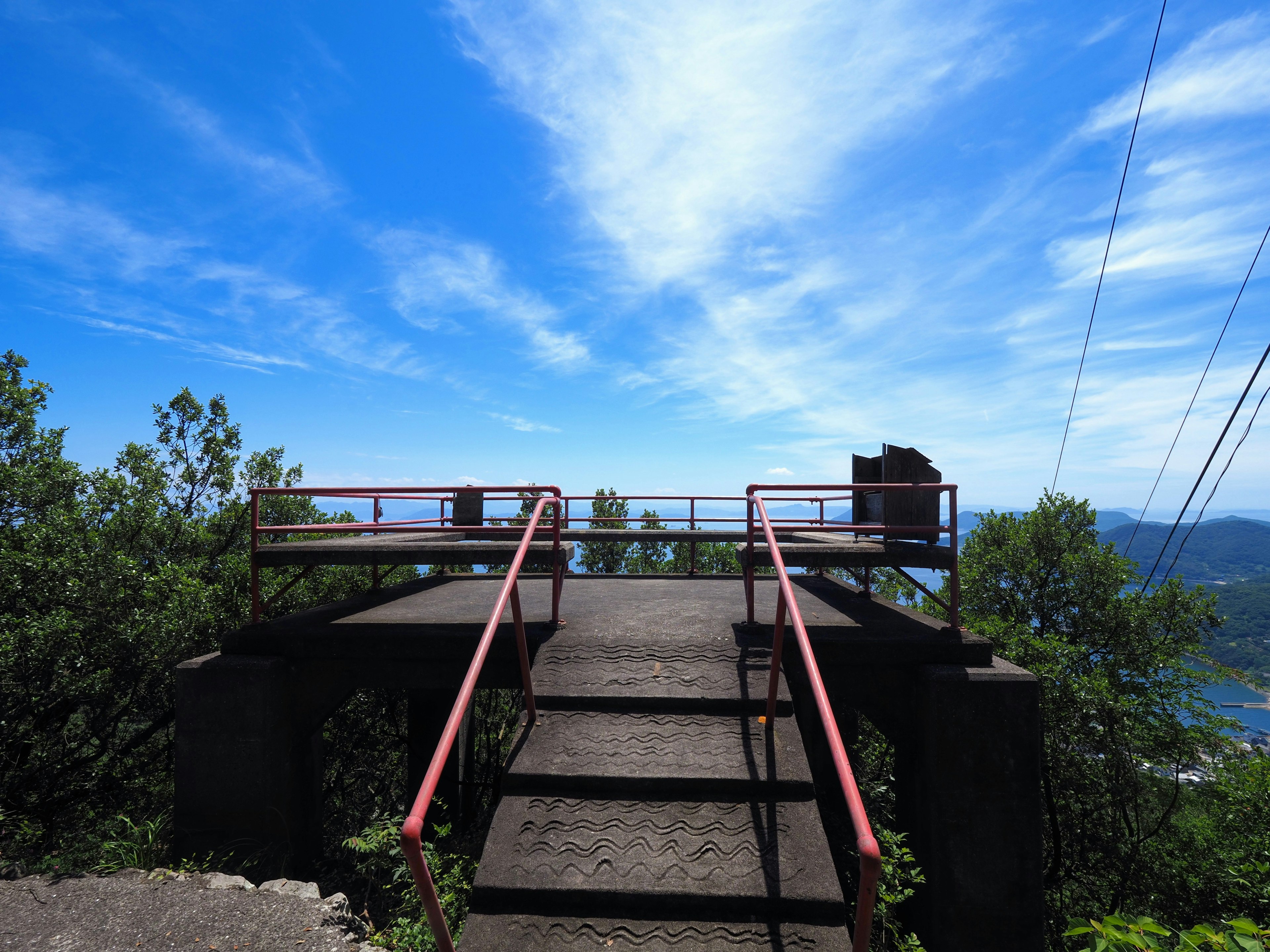 Aussichtsplattform mit Treppen und Geländern unter blauem Himmel