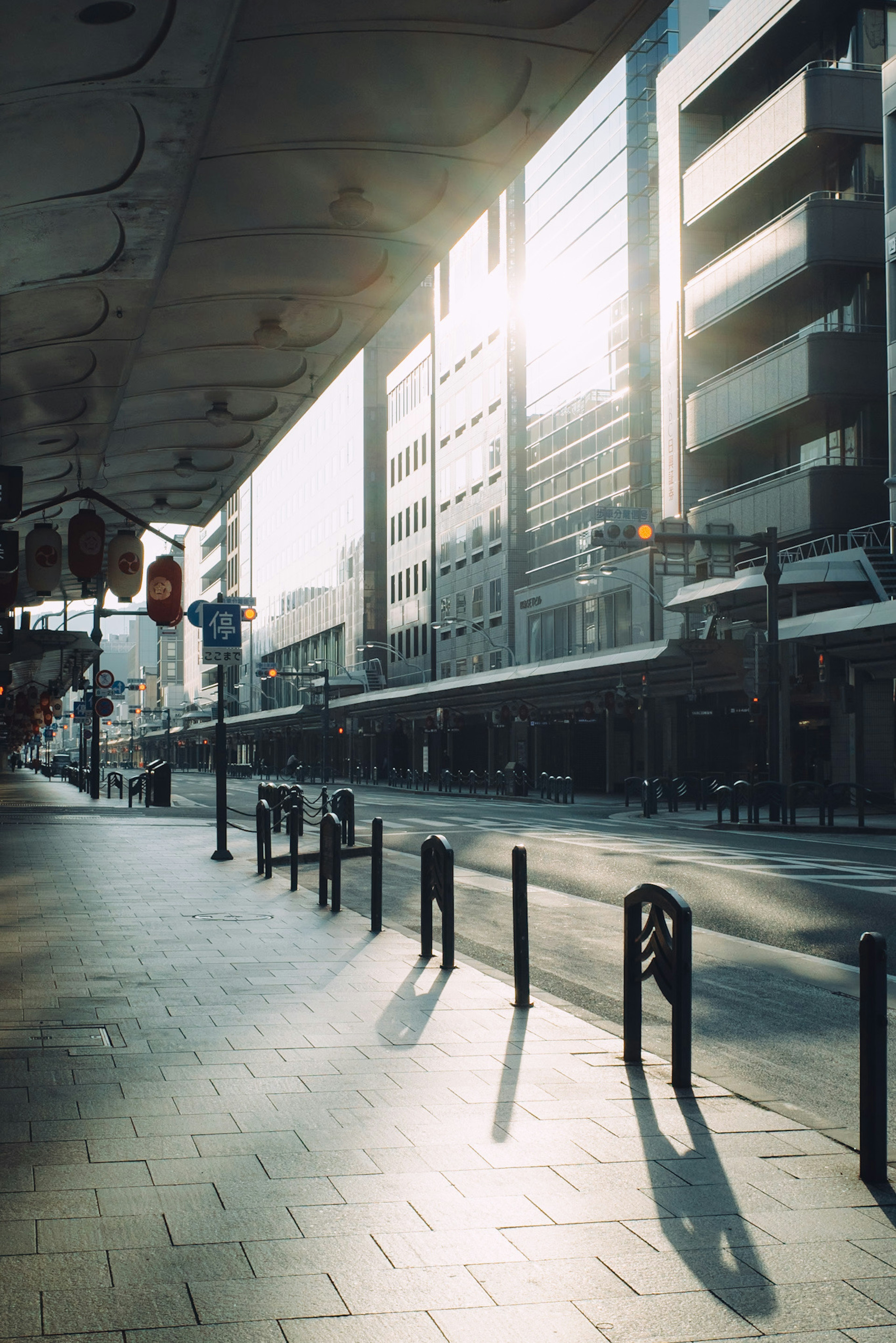 Eine Straßenszene mit Sonnenlicht, das zwischen den Gebäuden strömt, mit einer ruhigen Atmosphäre und minimalem Fußverkehr