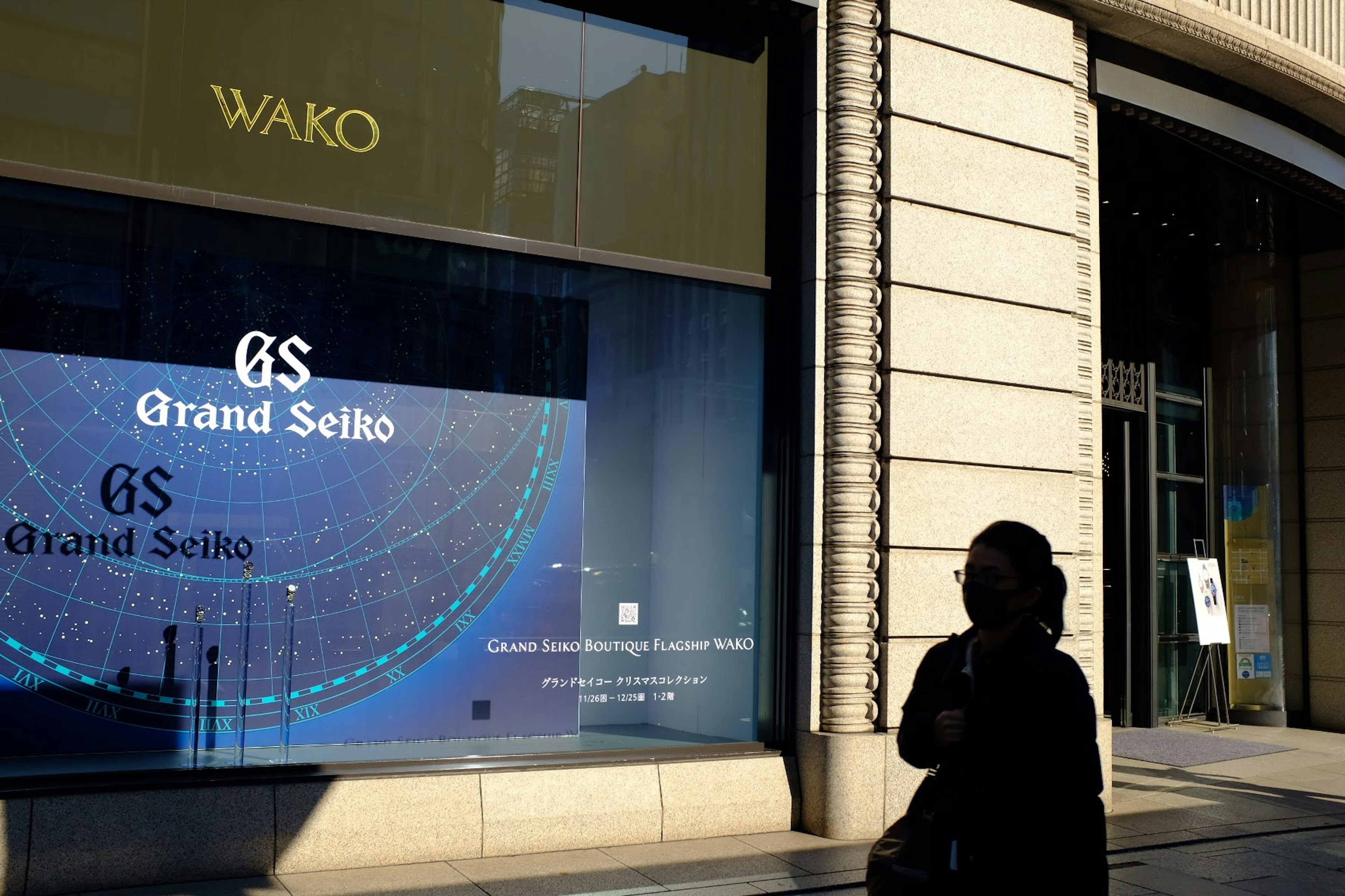 Silhouette of a person in front of a Grand Seiko display sign at WAKO store