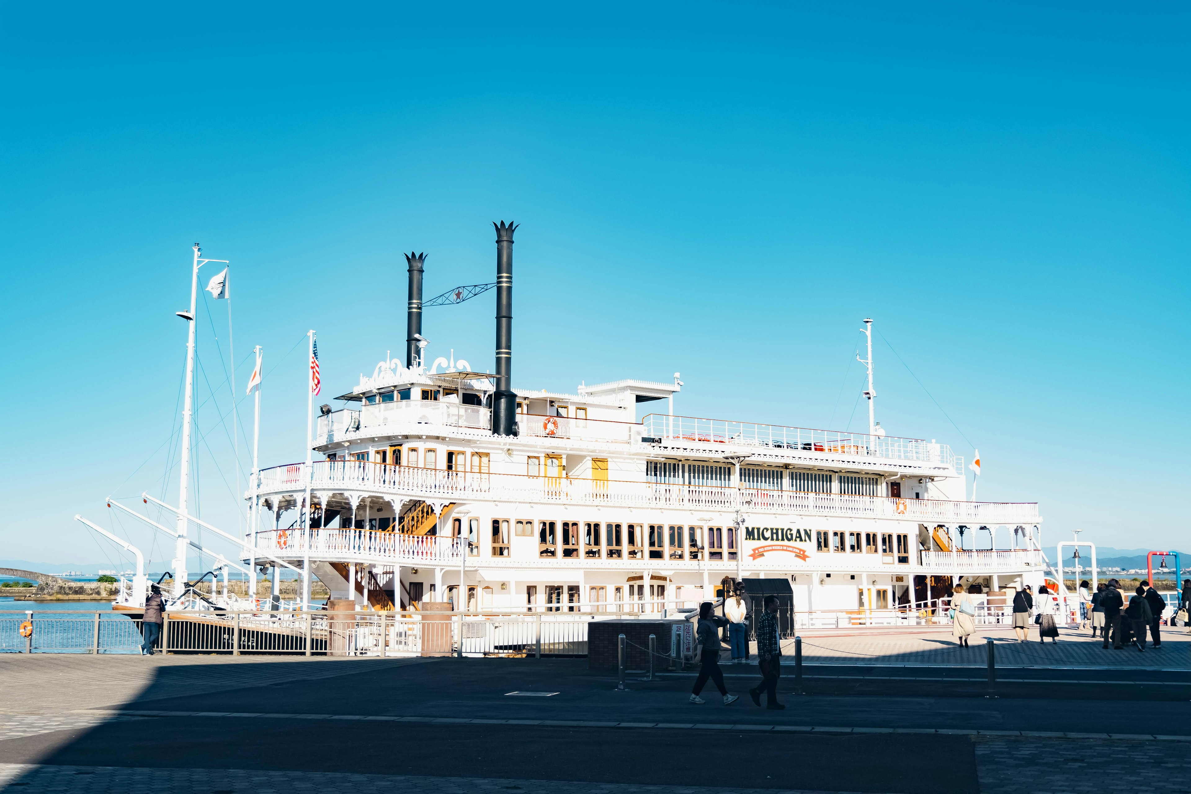 White riverboat docked under a clear blue sky with people nearby