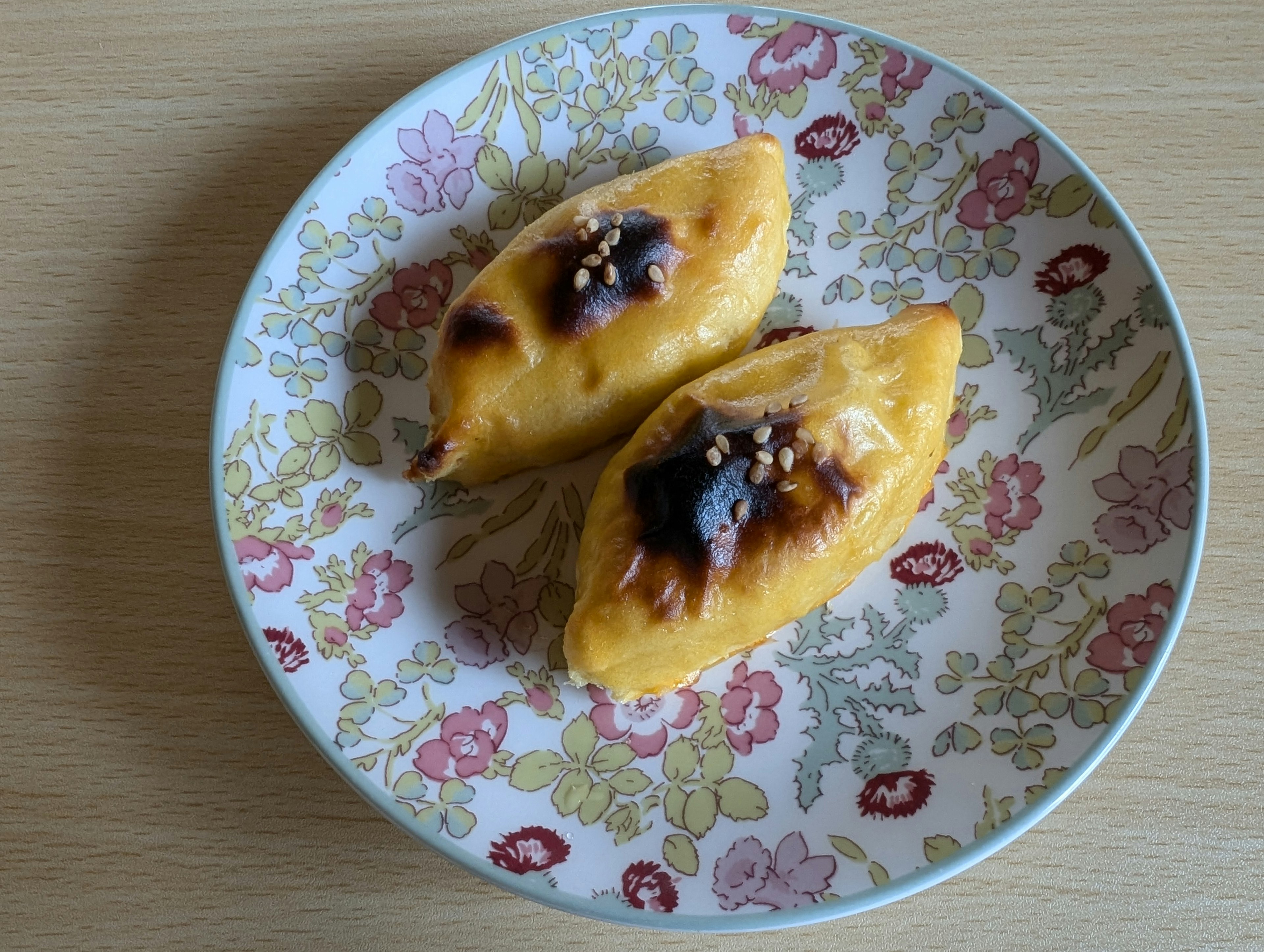 Two baked pastries on a floral plate topped with sweet bean paste