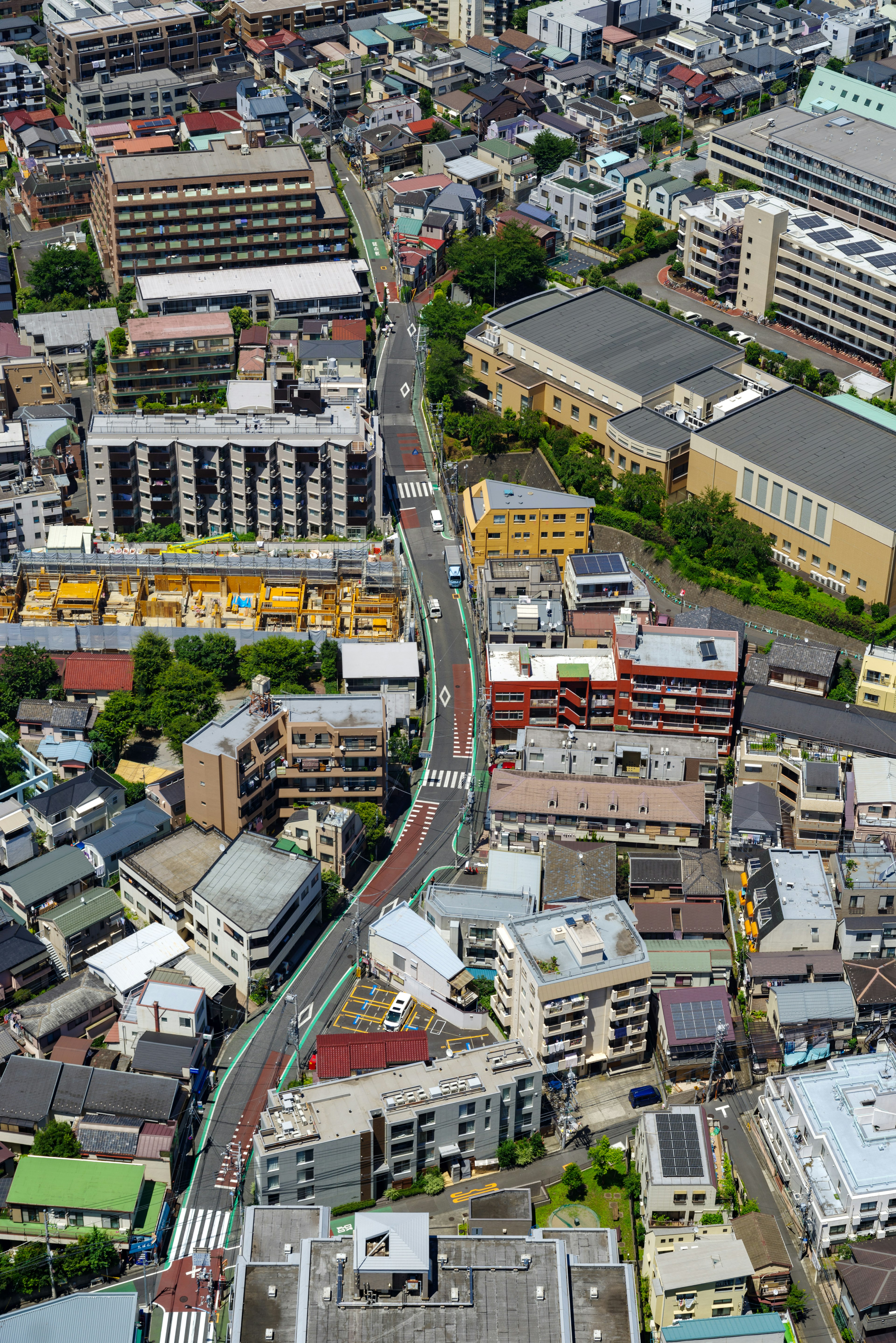 Aerial view of an urban landscape featuring various buildings and winding roads with green spaces