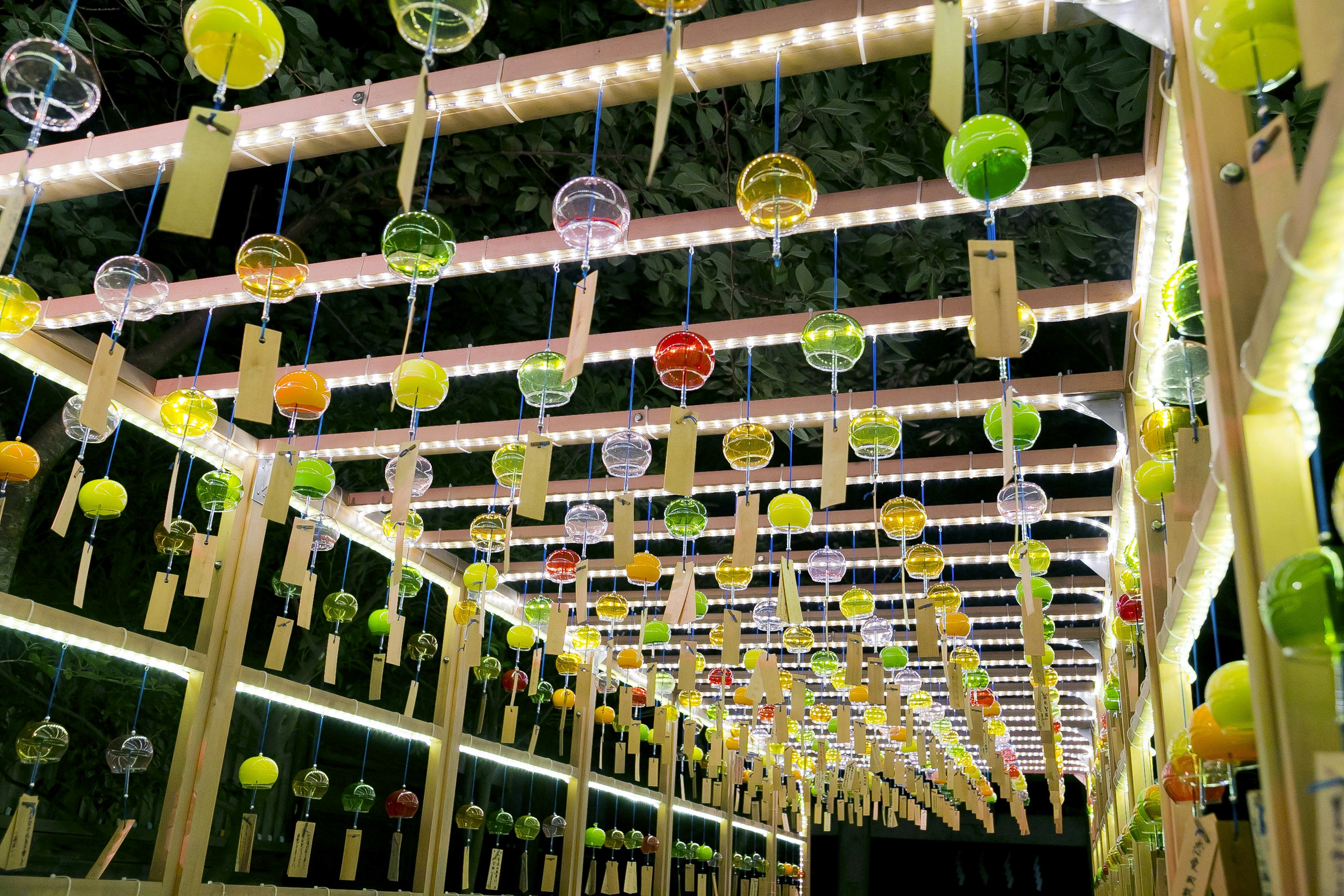 Campanas de viento coloridas colgadas en una exhibición interior con iluminación brillante