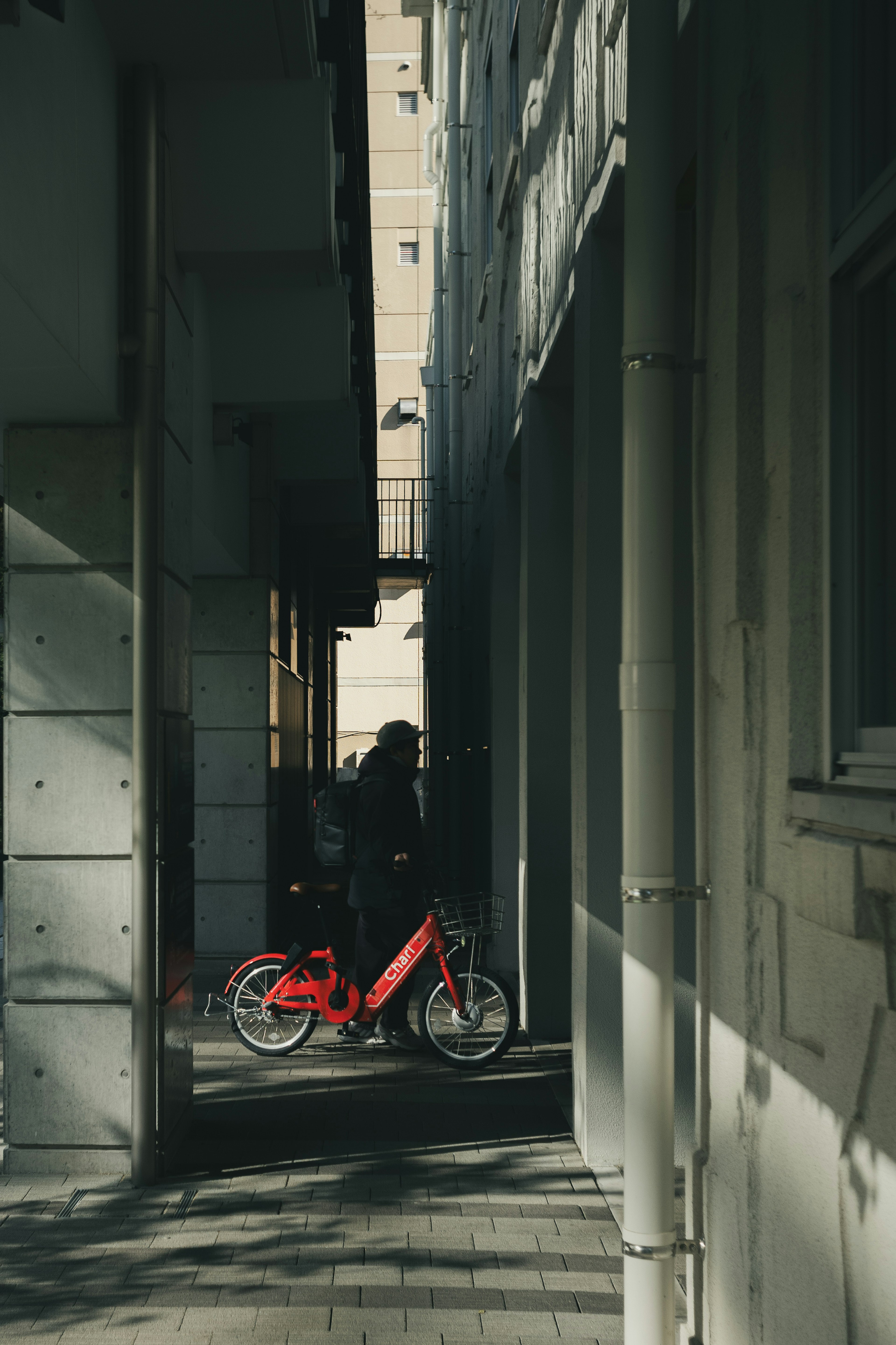 Une scène urbaine tranquille avec un vélo rouge garé dans une ruelle étroite