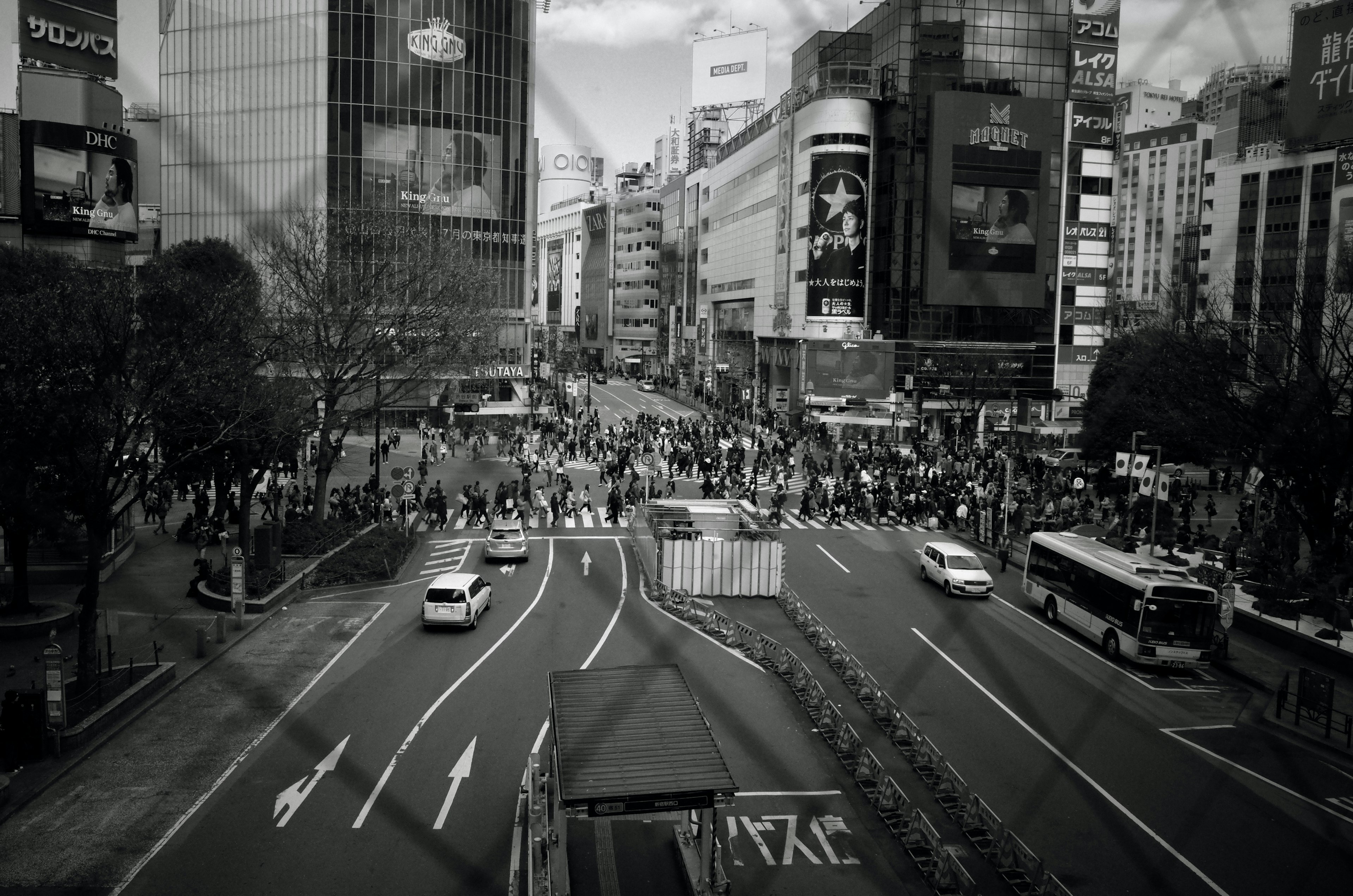 Foto hitam putih yang menangkap persimpangan sibuk di Tokyo dengan orang-orang yang menyeberang