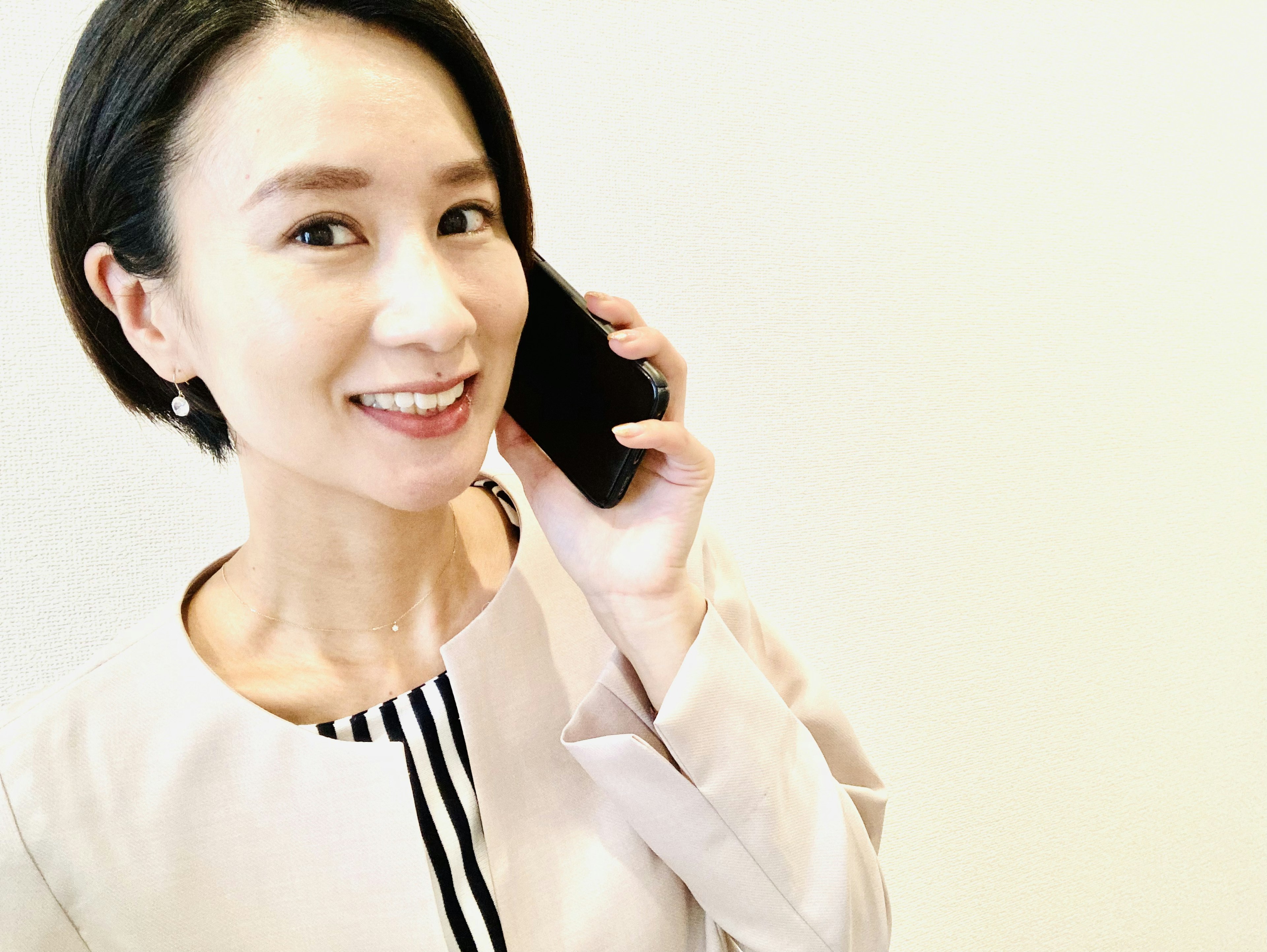 Femme souriante parlant au téléphone devant un fond blanc