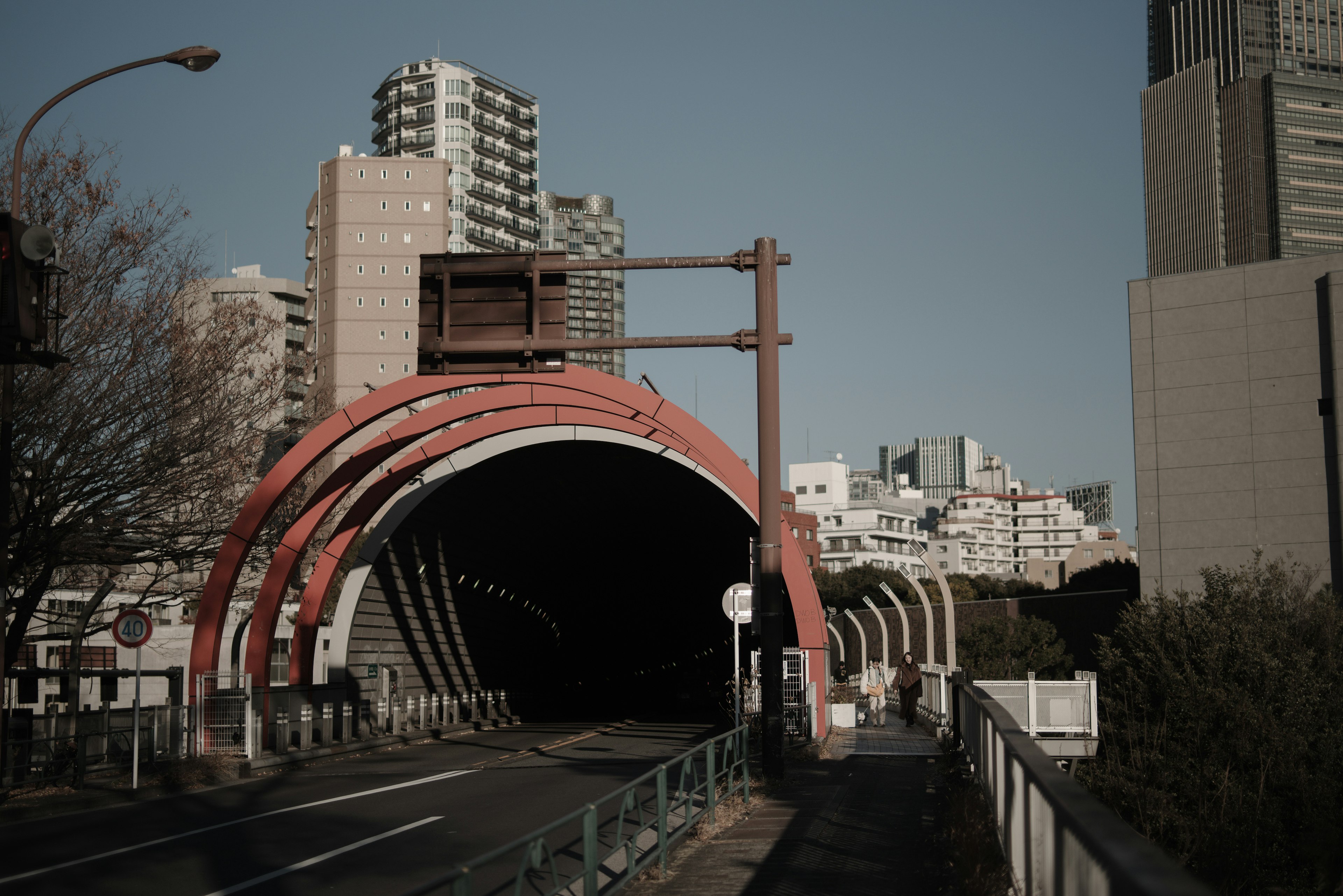 Entrance of a tunnel with distinctive red arches and surrounding skyscrapers