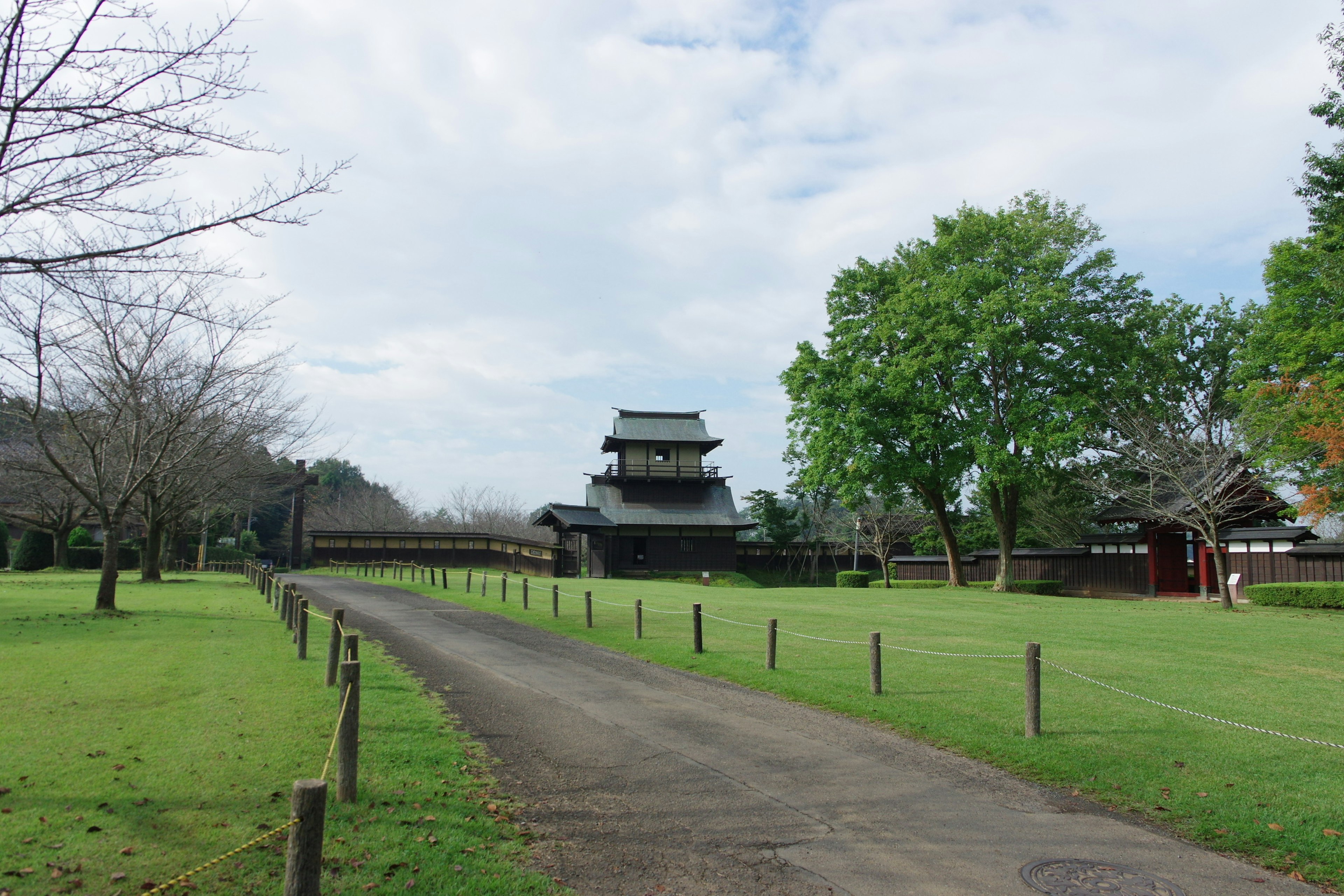 Vue d'un château japonais entouré d'herbe verte et d'un chemin