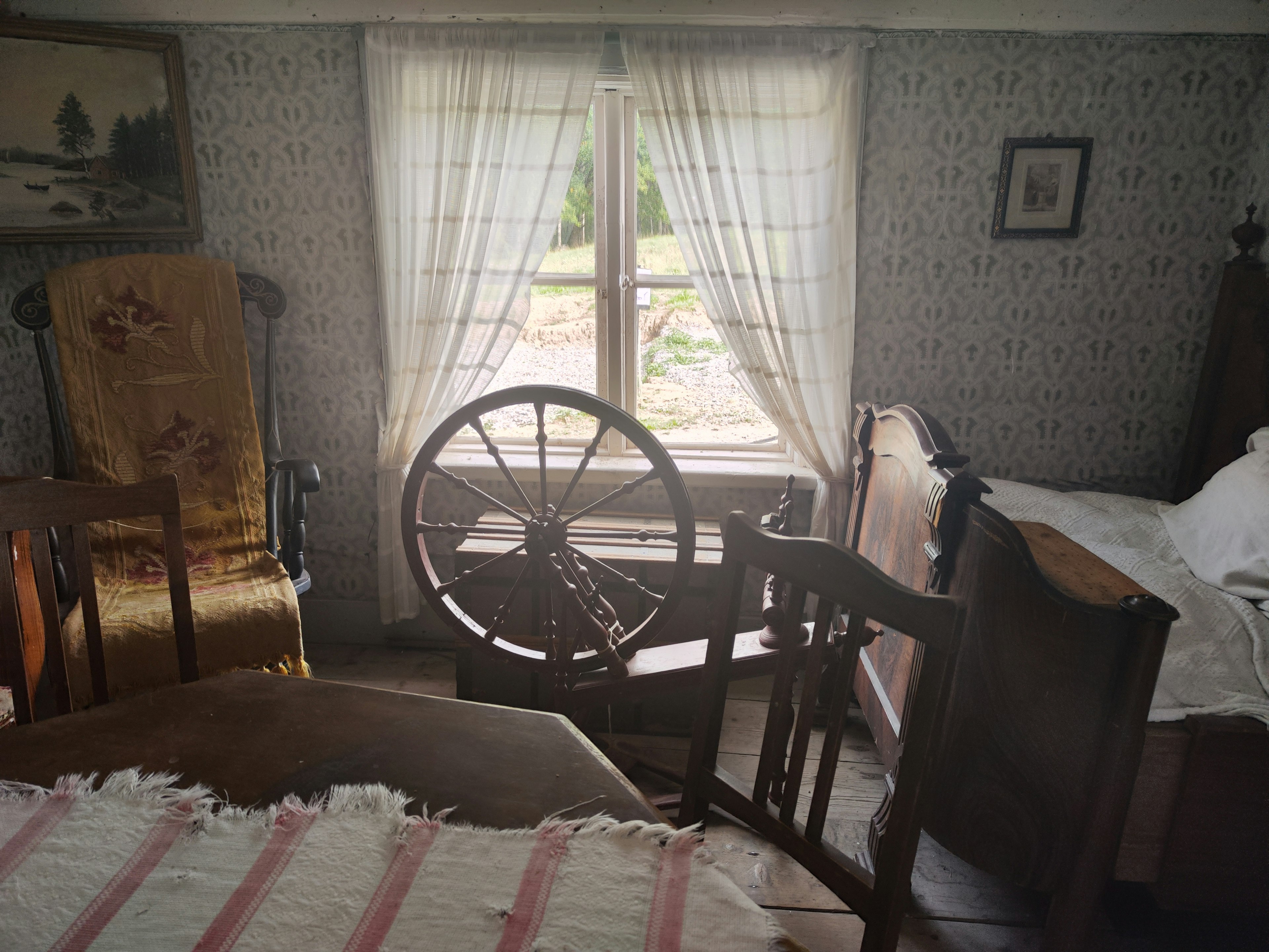 Intérieur d'une chambre vintage avec des meubles en bois et un rouet près d'une fenêtre