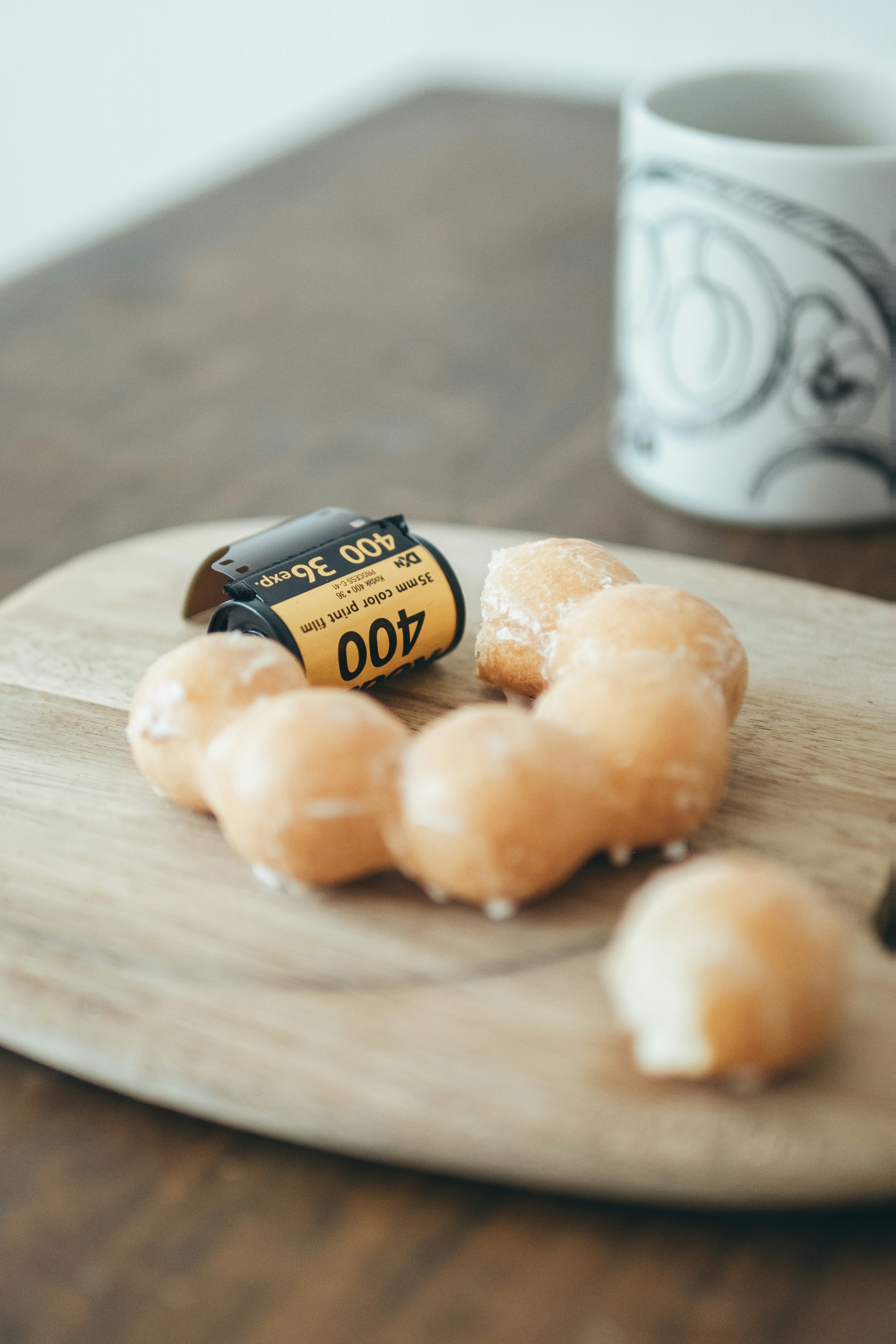 A film roll next to glazed donuts on a wooden platter