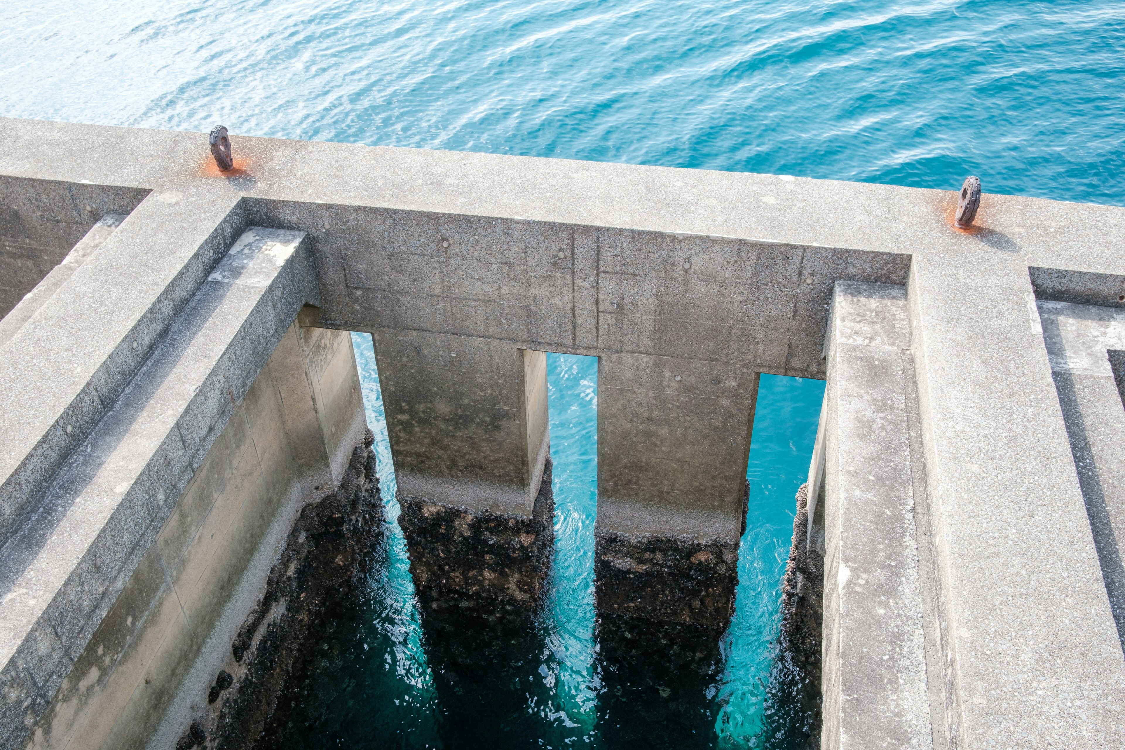 Muelle de concreto con soportes visibles sumergidos en agua clara