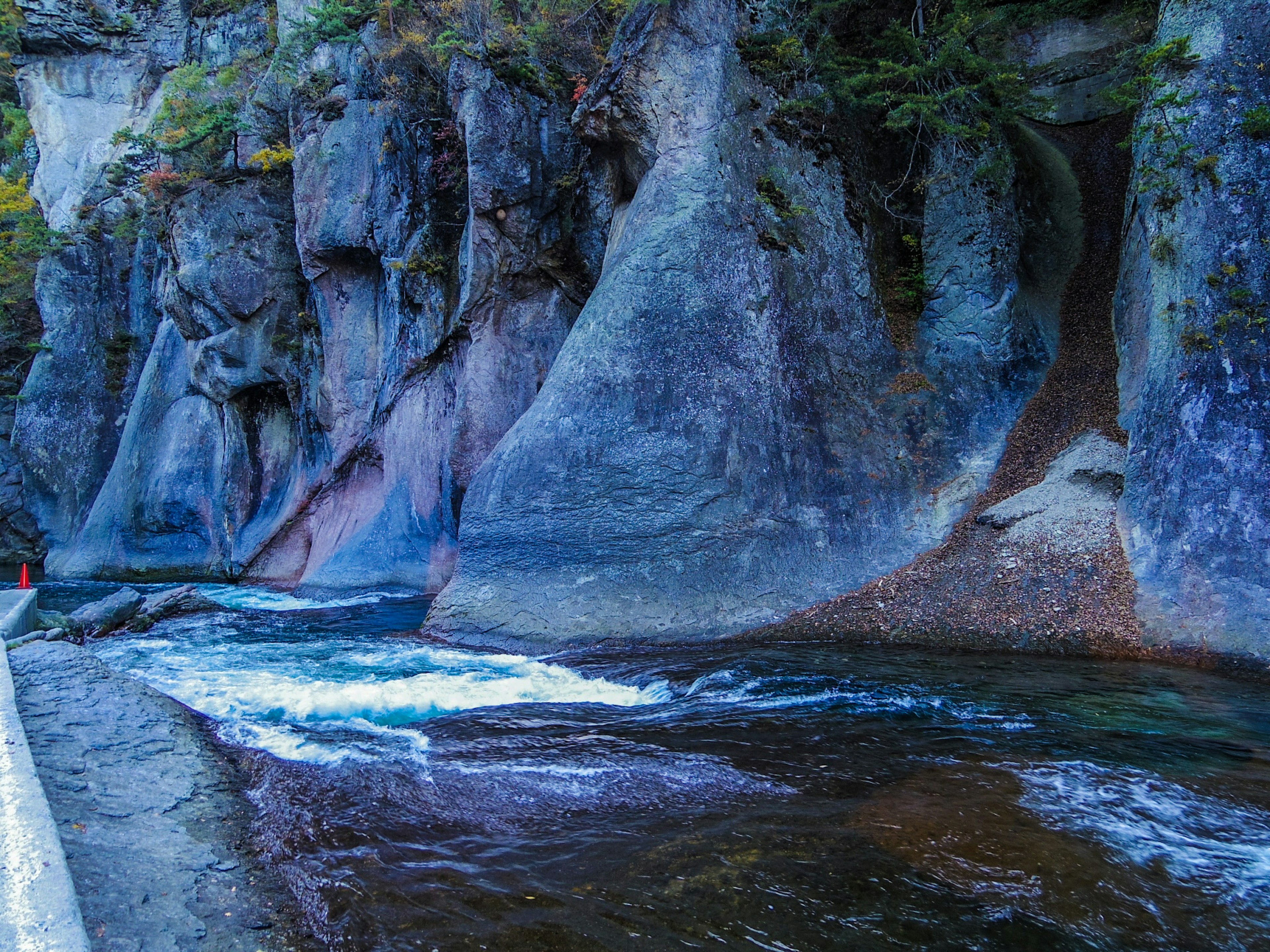 Vista escénica de un río azul fluyendo junto a formaciones rocosas escarpadas