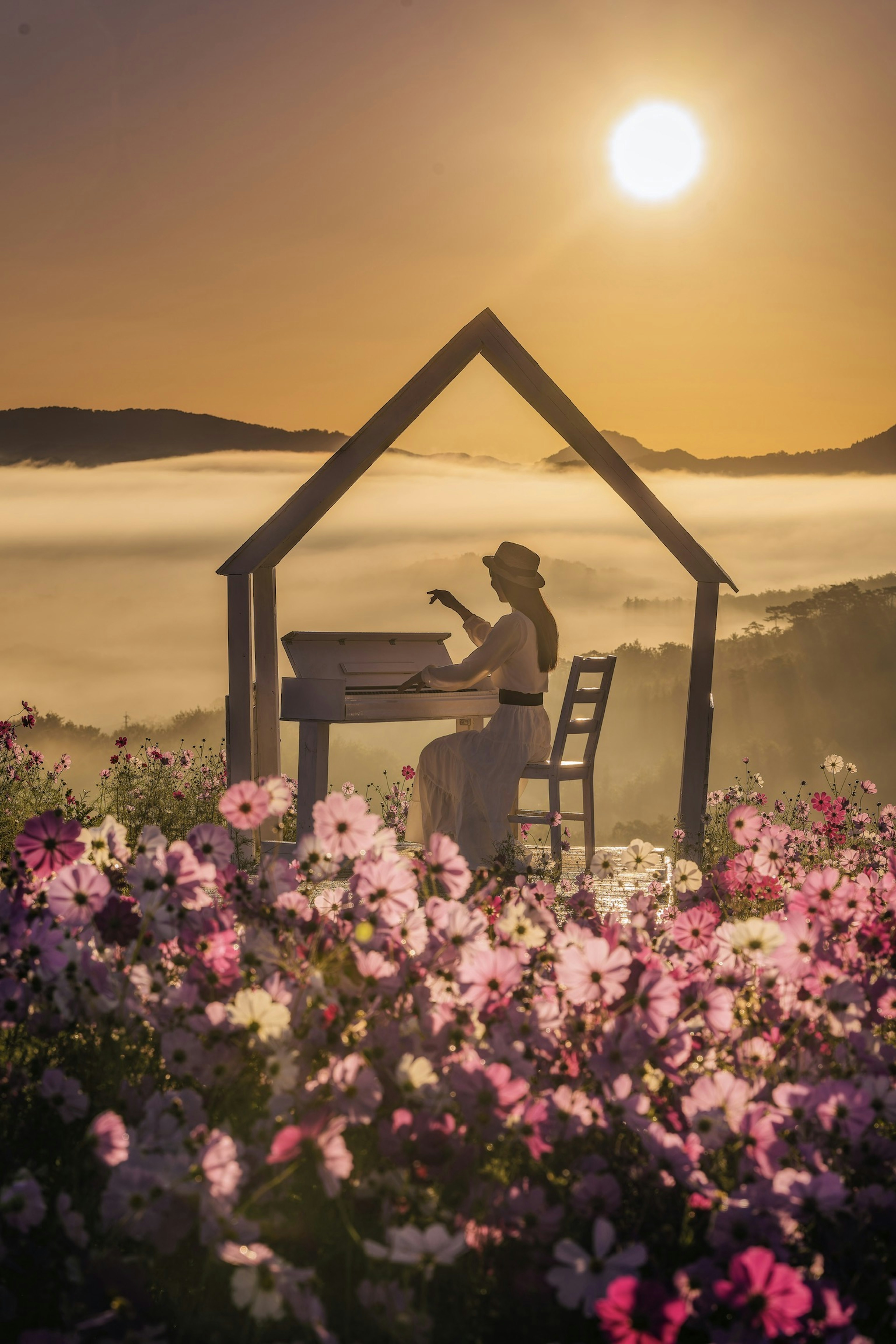 Eine Frau spielt ein Musikinstrument umgeben von bunten Blumen bei Sonnenuntergang