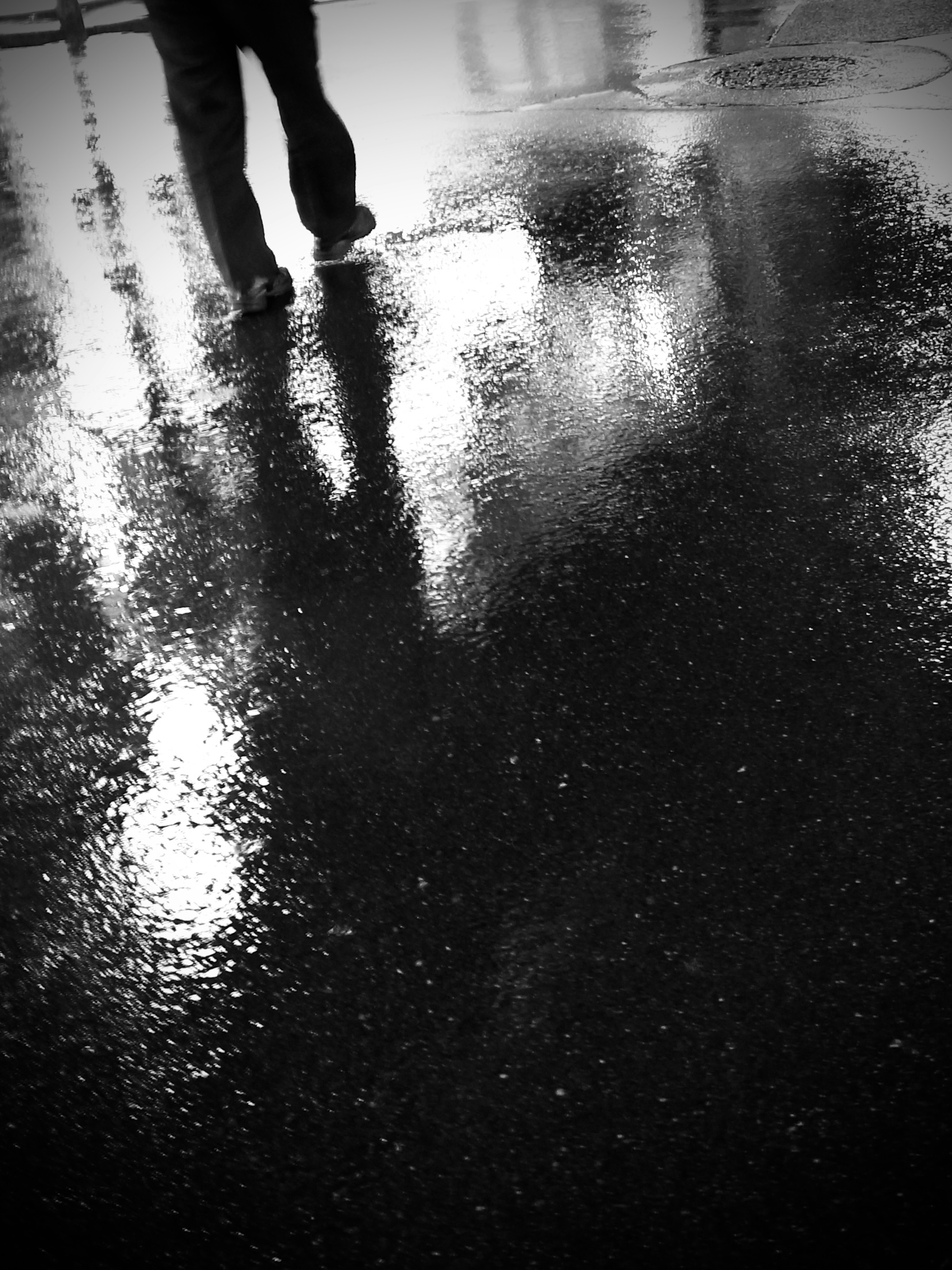 Silhouette of a person walking on a rain-soaked surface with reflections