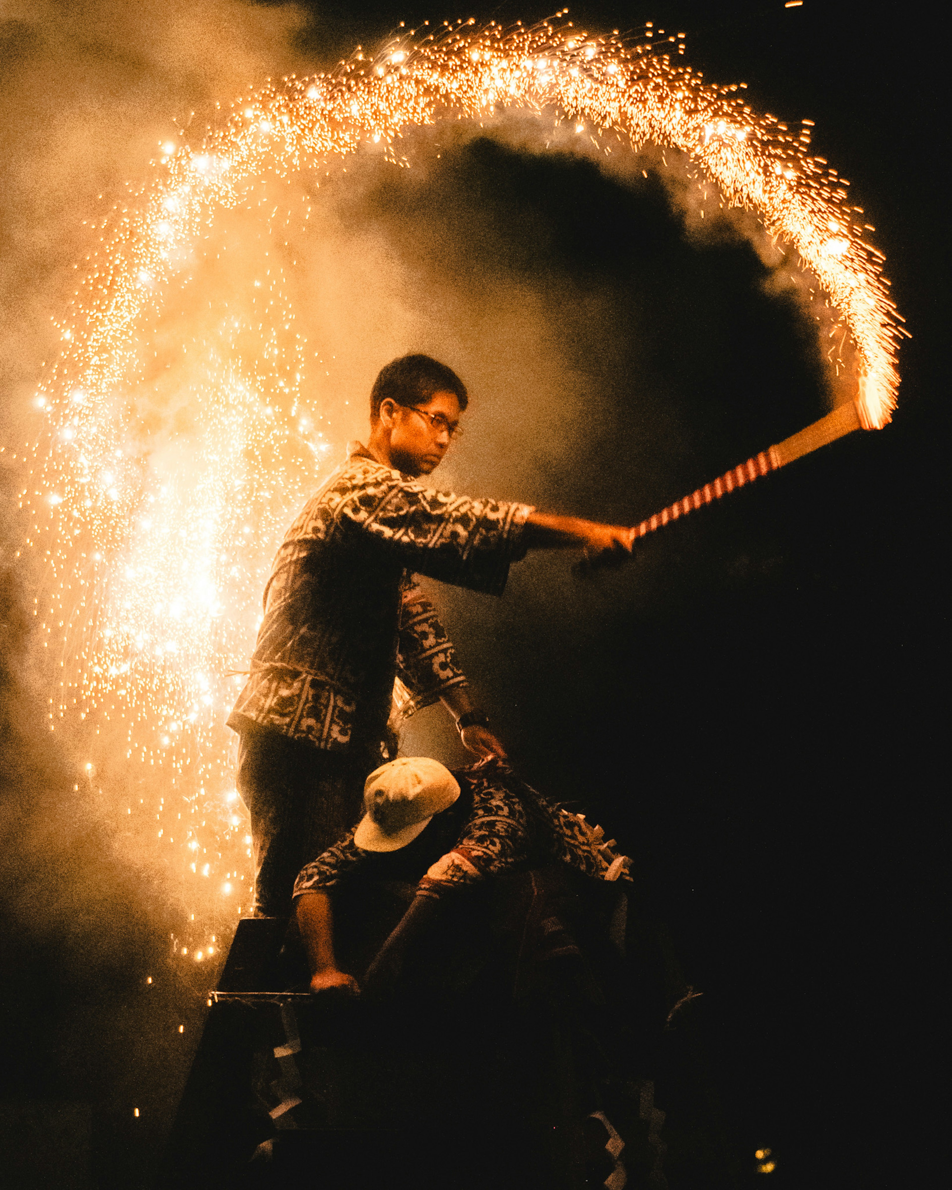 Performance avec un homme agitant une étincelle contre un fond sombre et une autre personne derrière