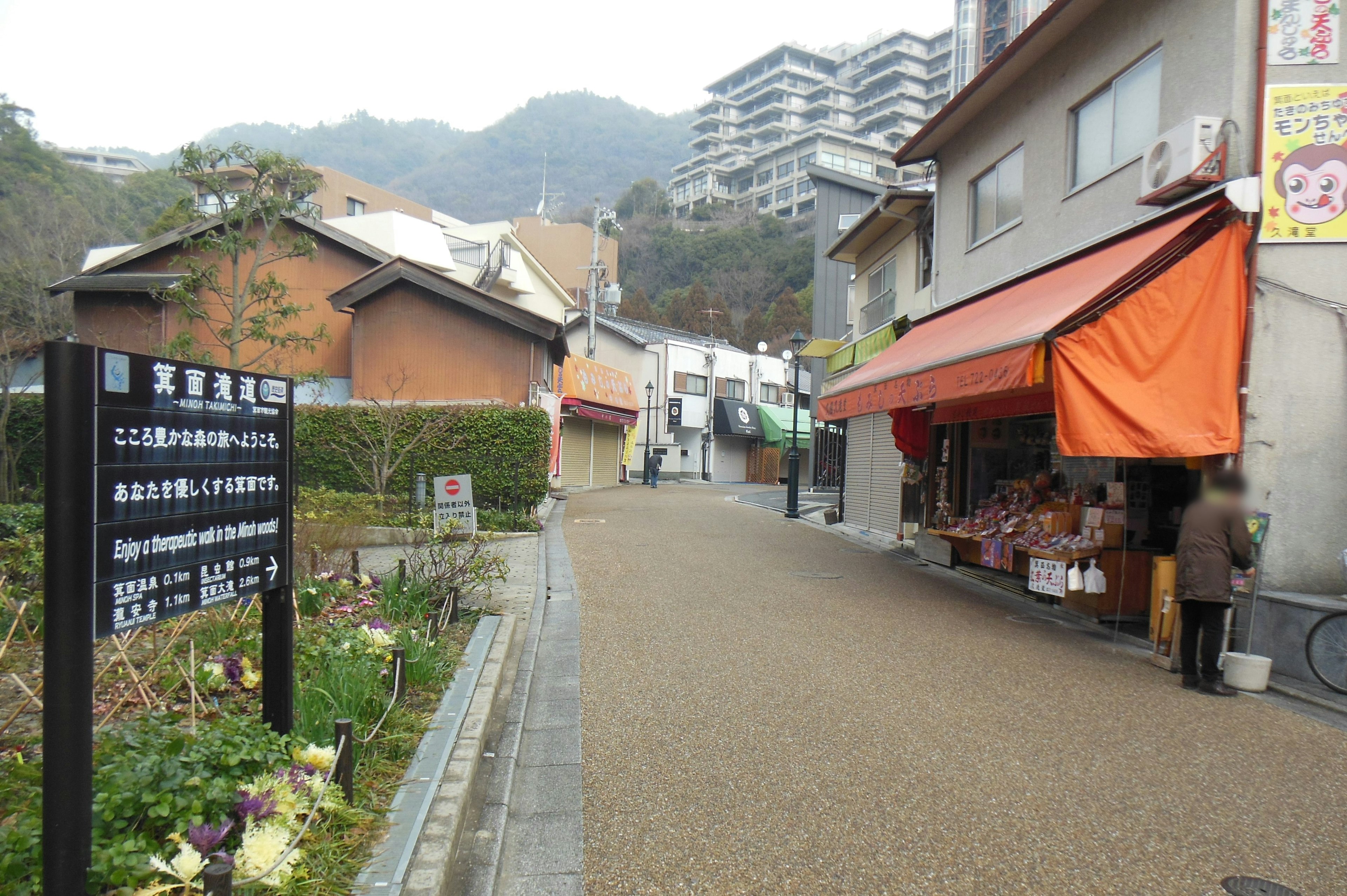 ถนนเงียบสงบที่มีร้านค้าและกันสาดสีส้มสดใสตั้งอยู่ท่ามกลางภูเขา