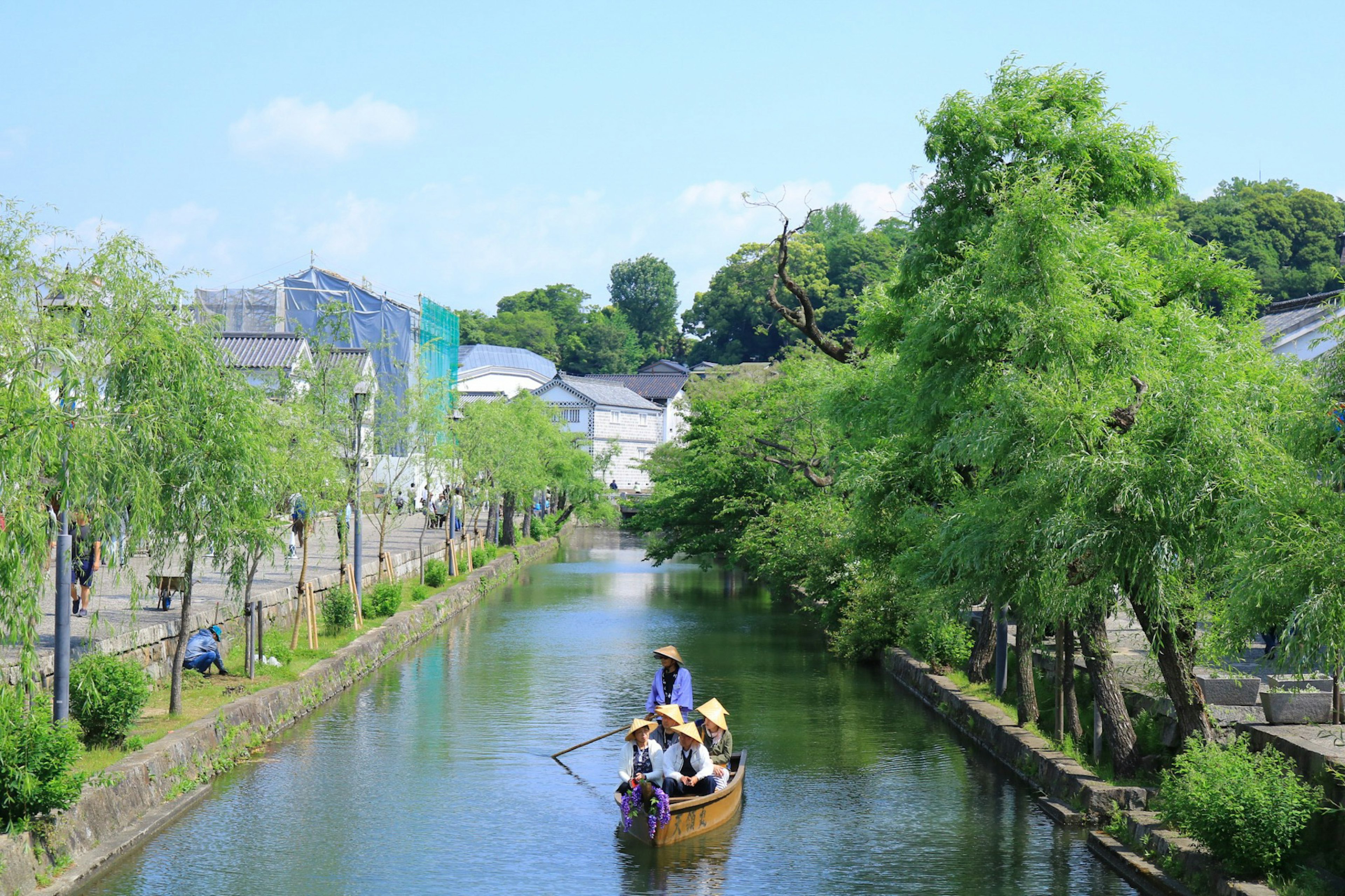 静かな川を漕ぐ小舟と緑に囲まれた風景