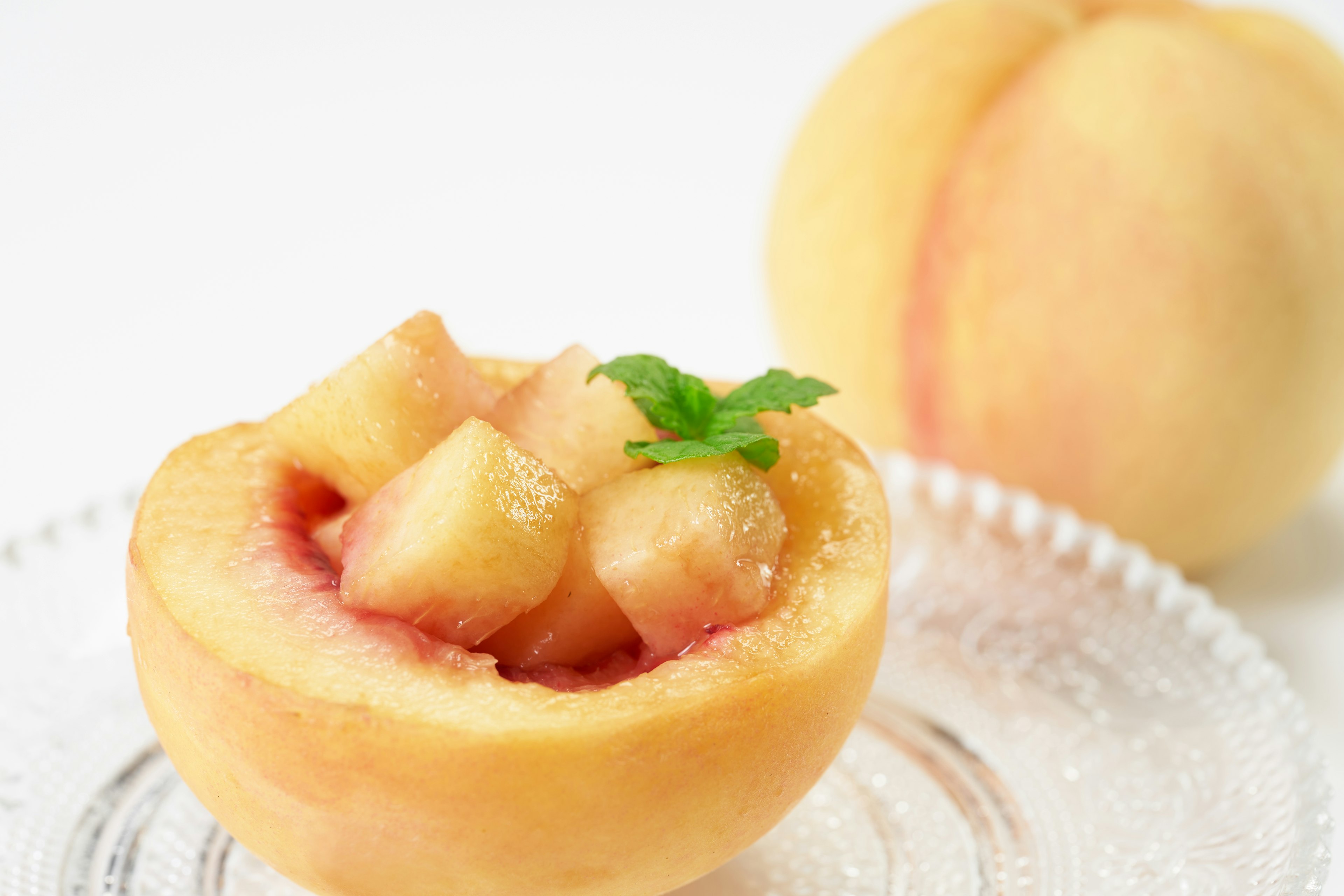 Mitad de durazno fresco rellena de fruta en cubos y hojas de menta