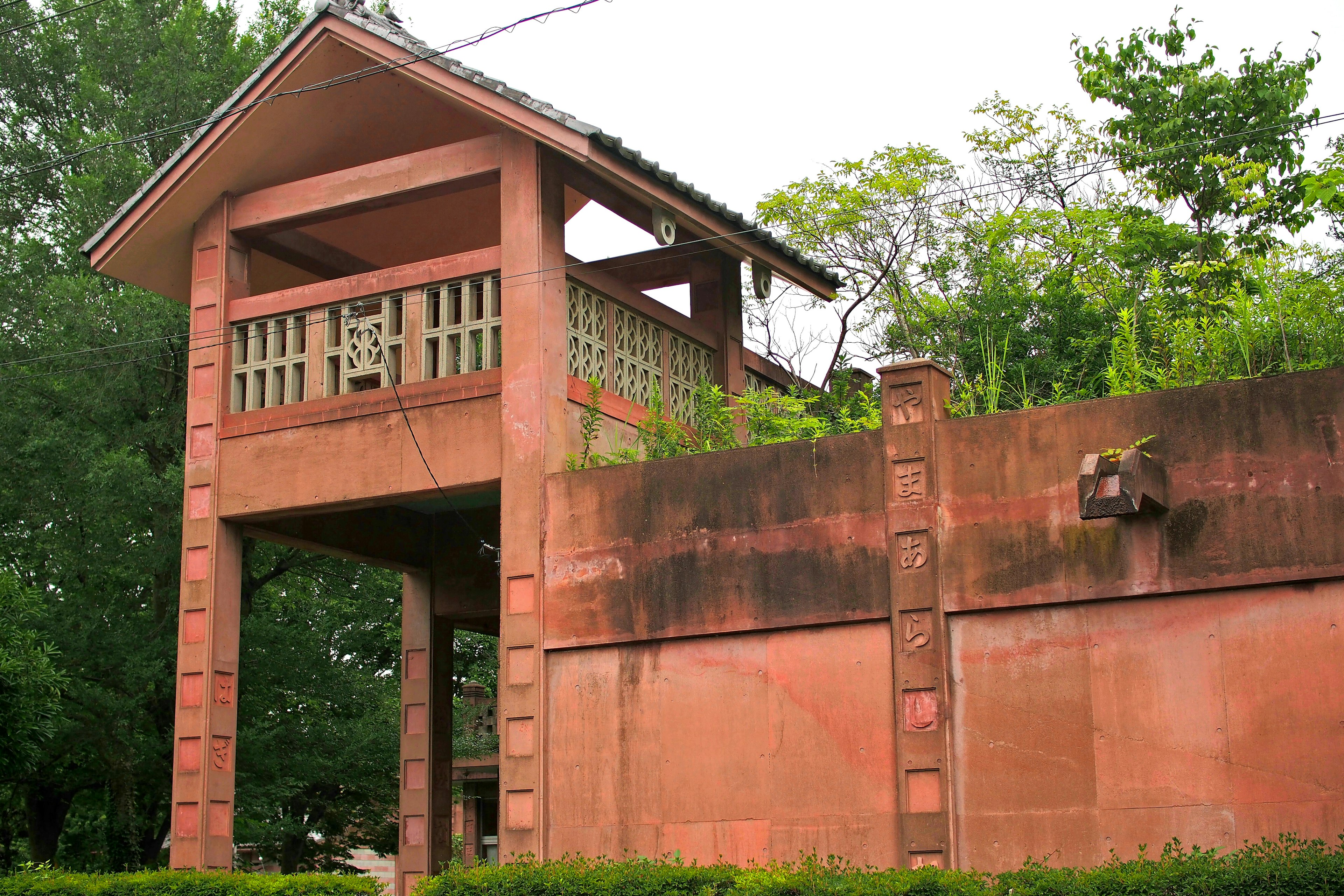 茶色の壁と緑の木々に囲まれた高台の建物の構造