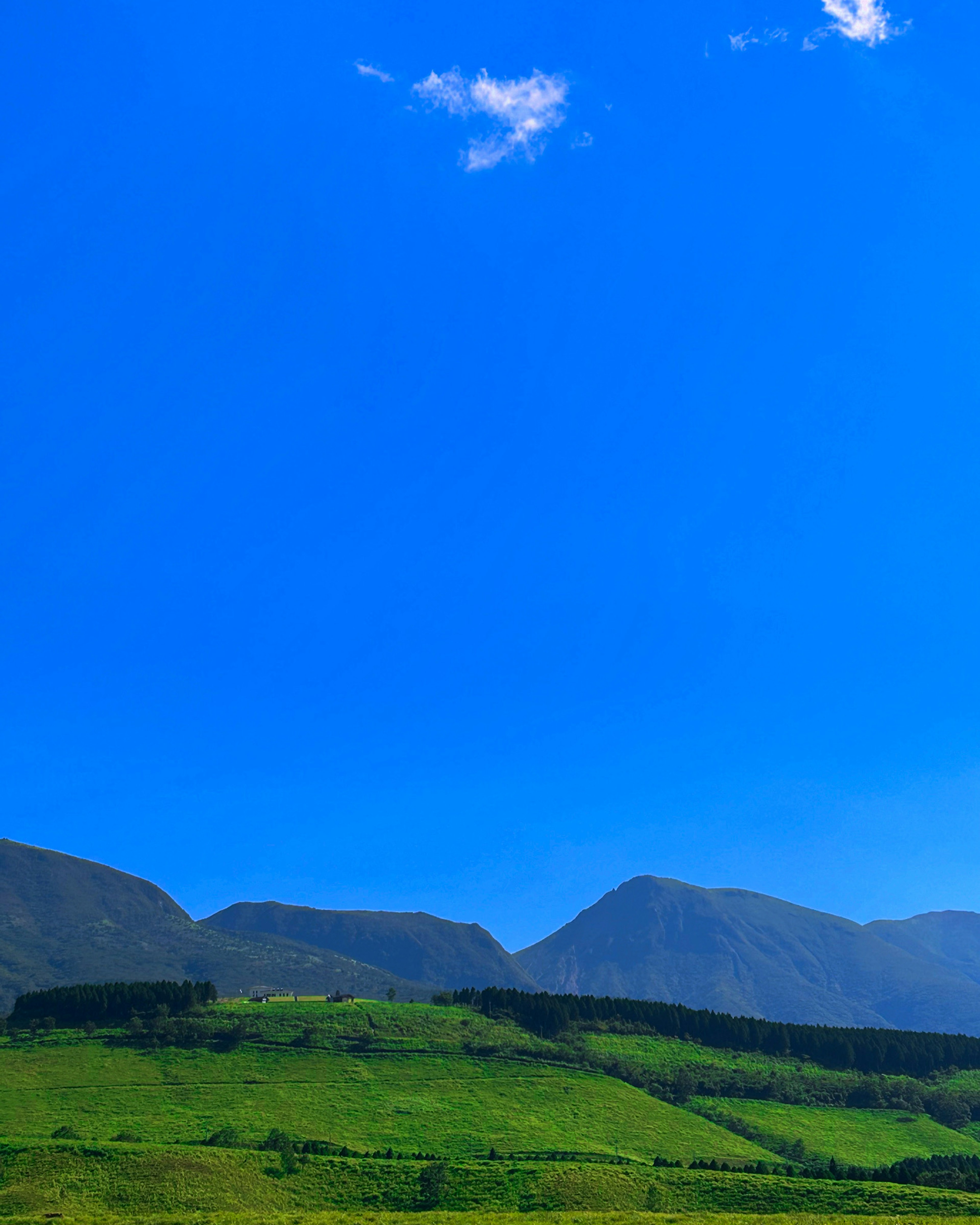 Ciel bleu vif sur des collines et montagnes verdoyantes