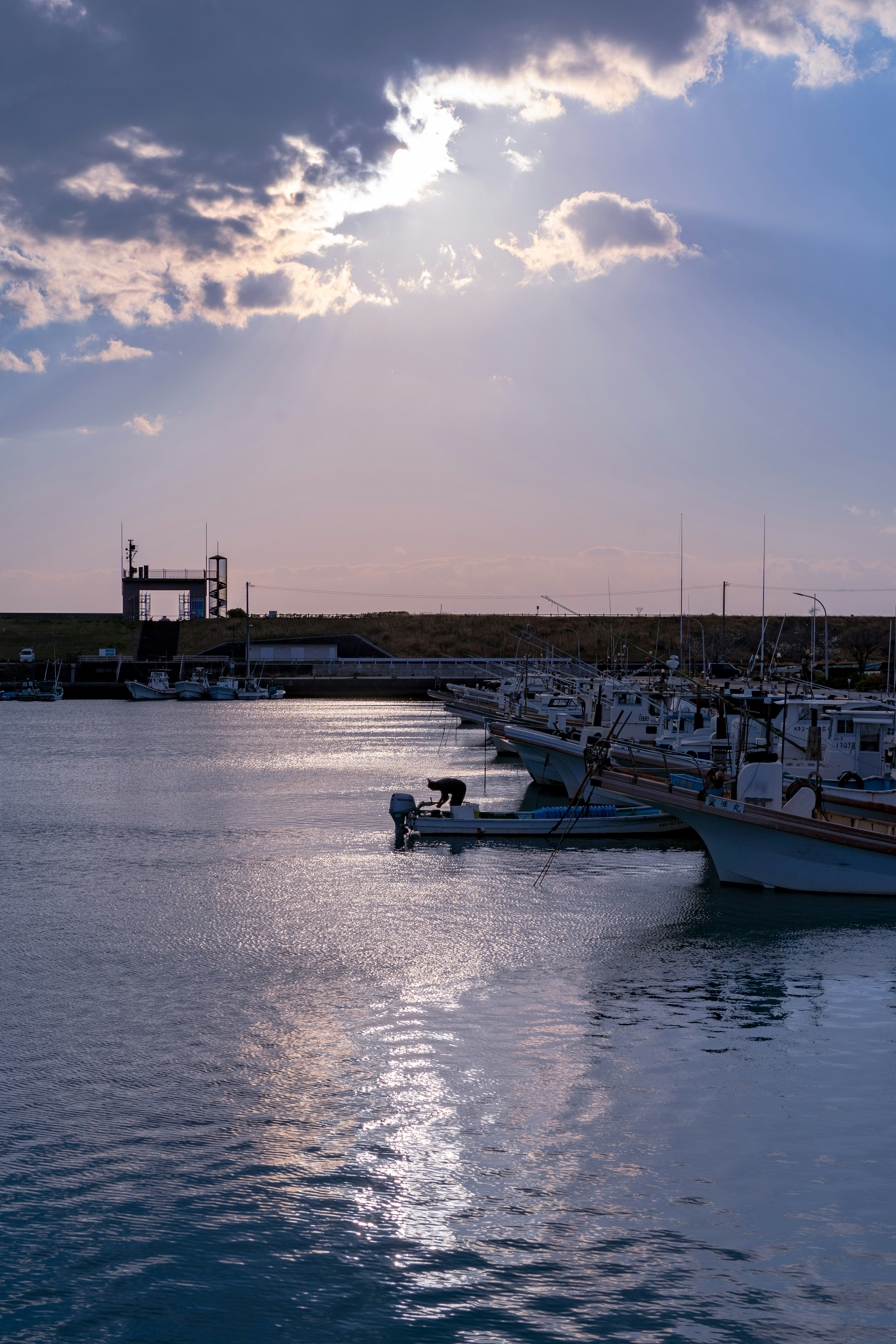 Barcos atracados en un puerto con un cielo de atardecer reflejado en aguas tranquilas