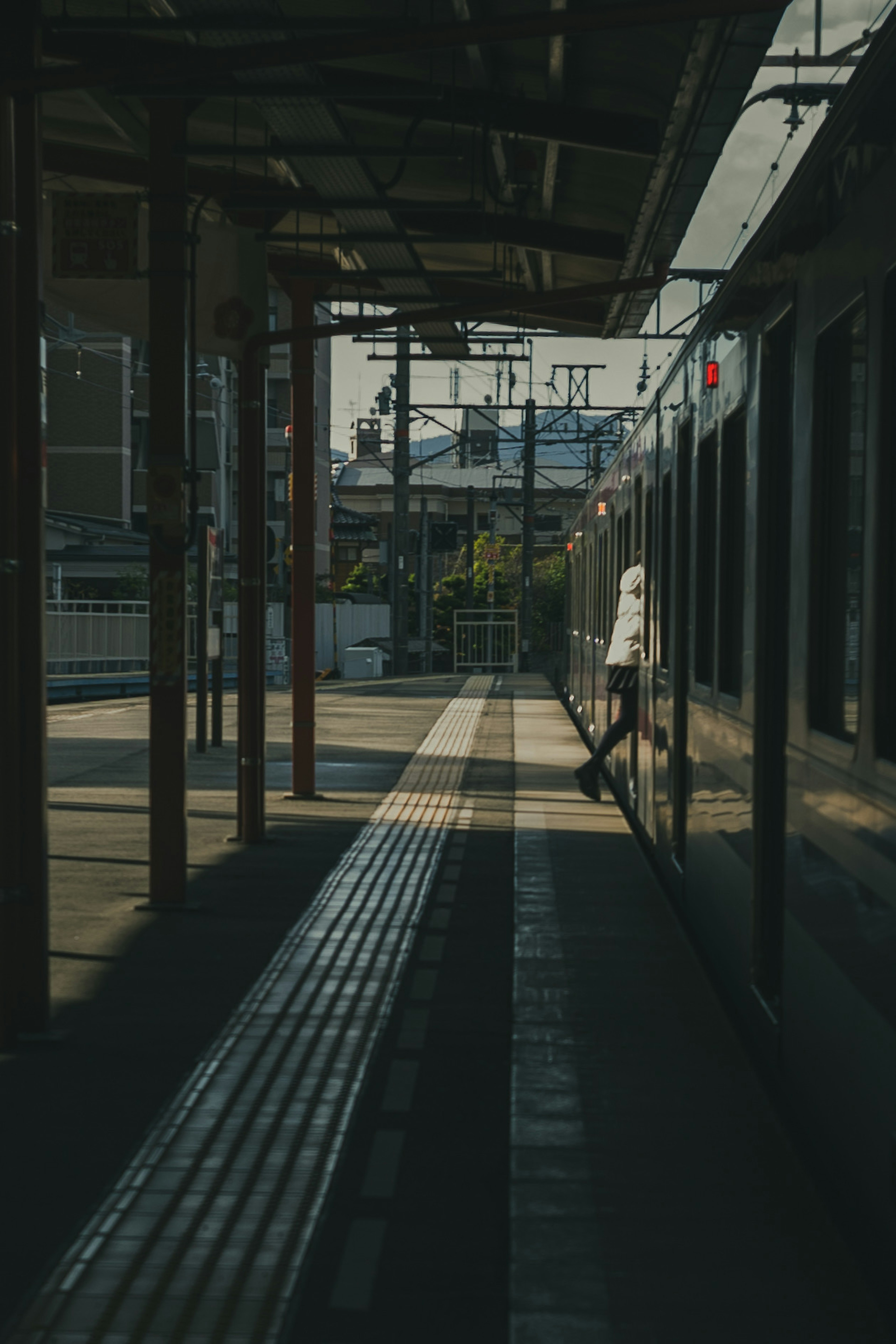 Silhouette di una persona su una banchina di treno con un treno sullo sfondo