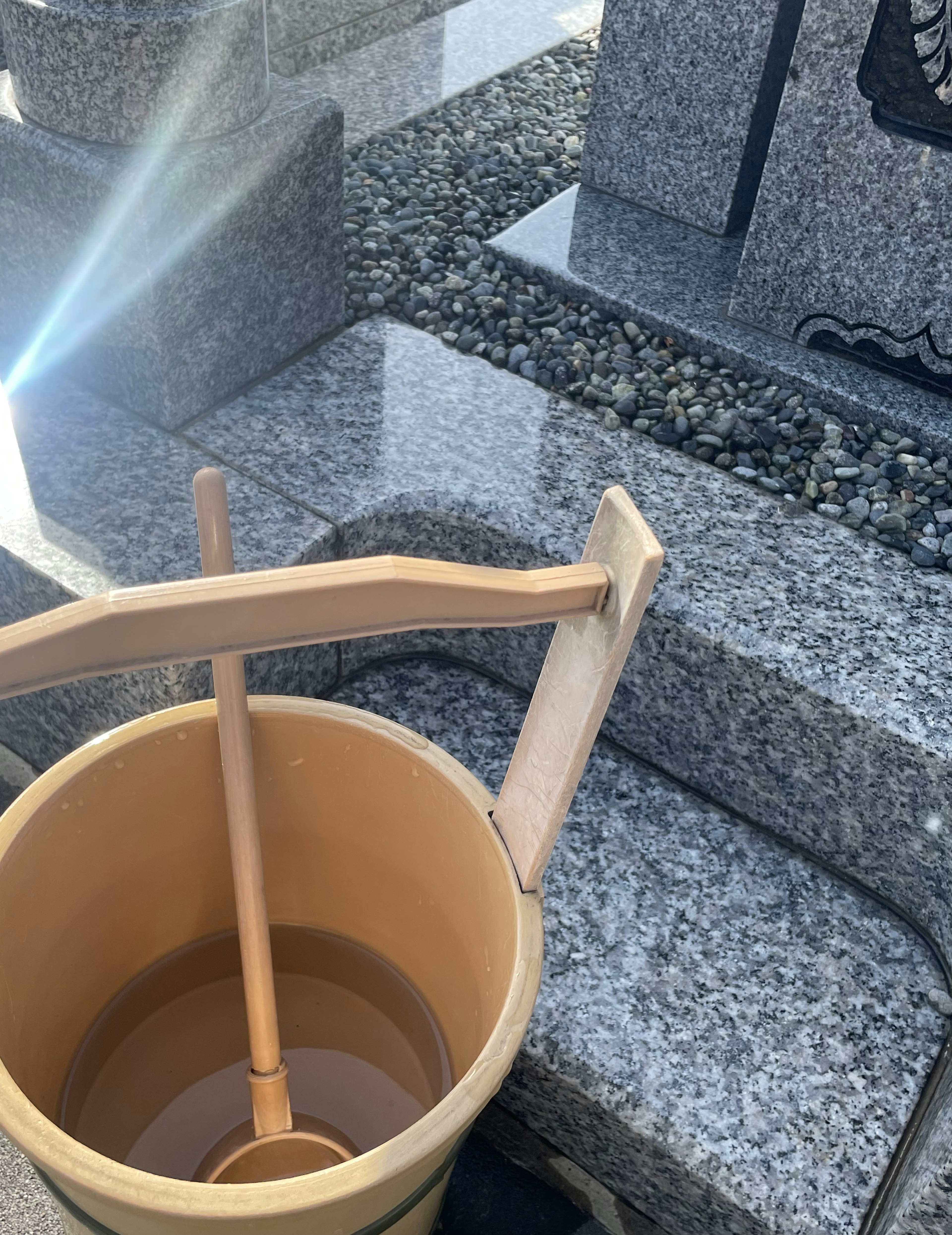 Seau d'eau avec une cuillère en bois dans un cimetière