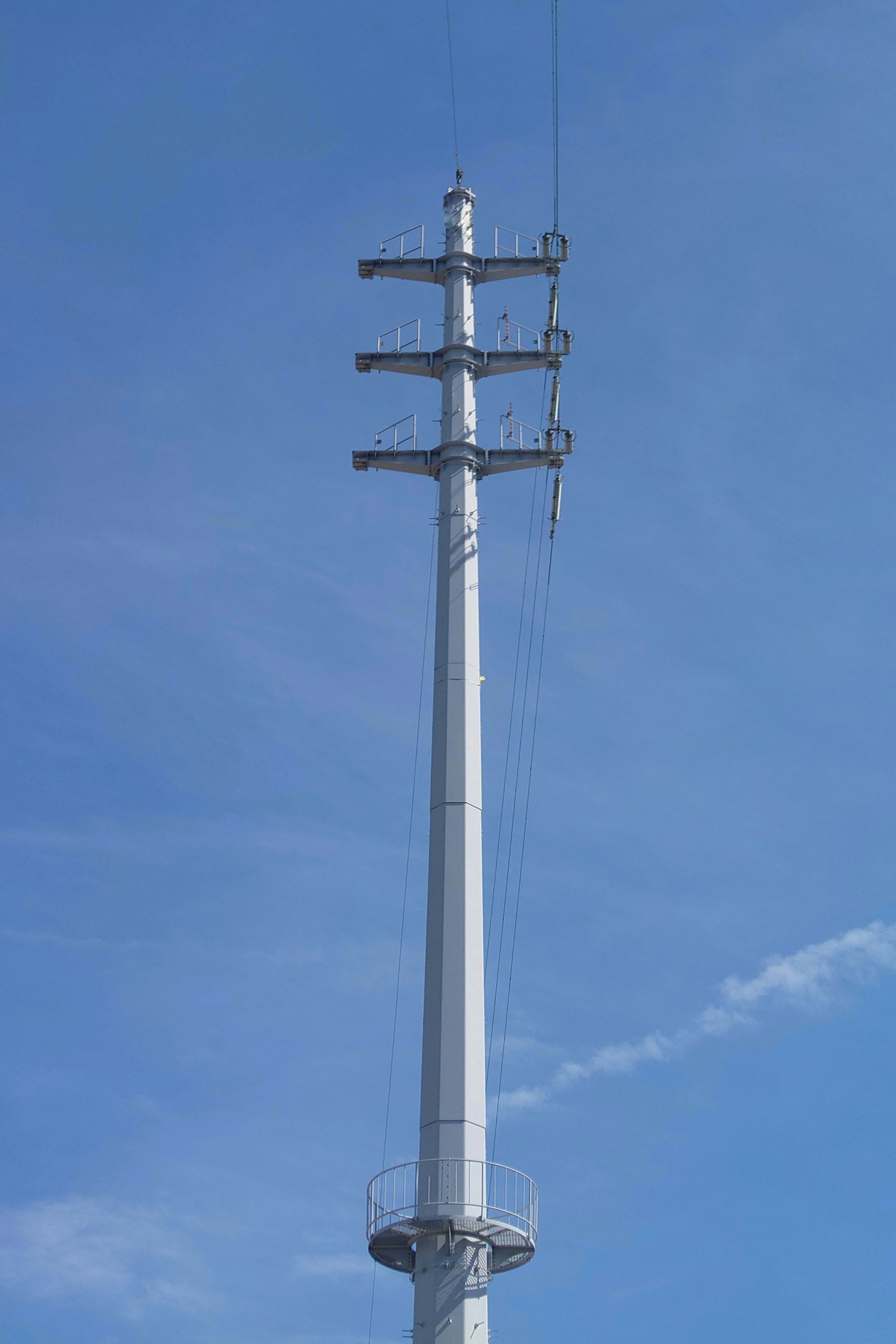 Una alta torre metálica con múltiples travesaños contra un cielo azul claro