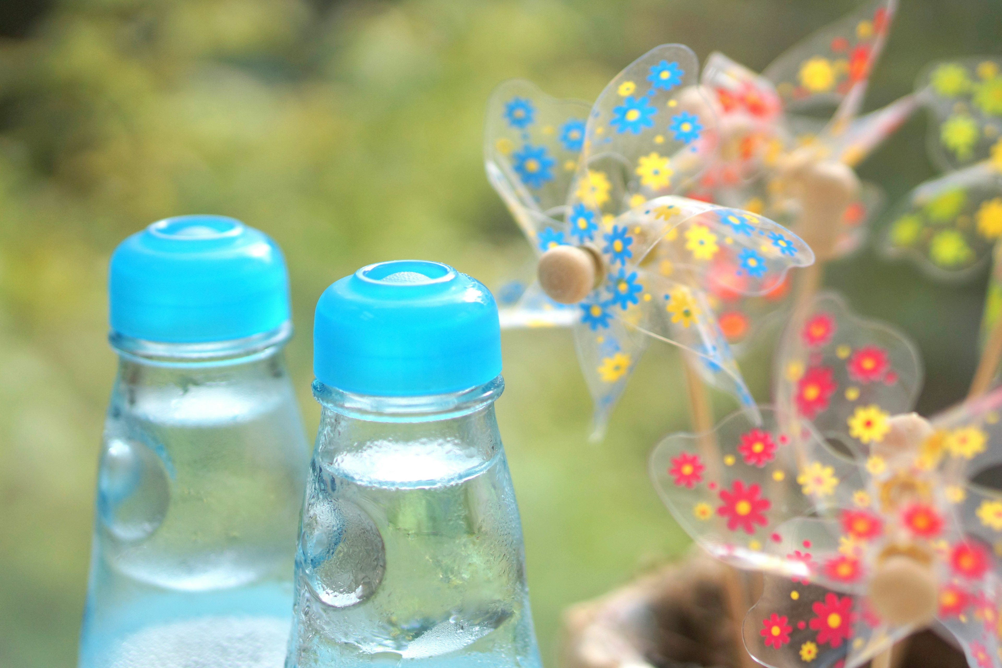 Two water bottles with blue caps and colorful flower decorations in the background