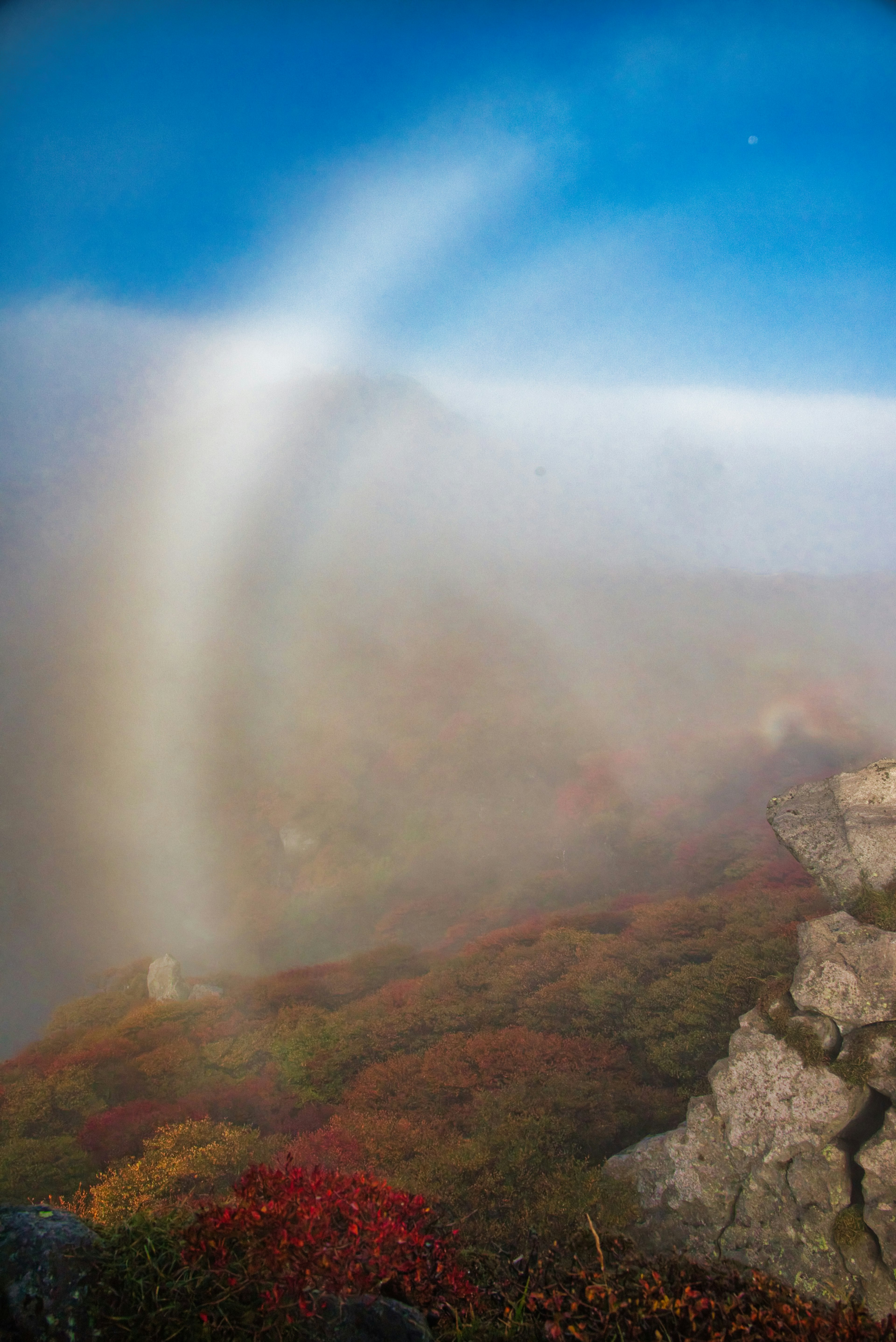 Eine Landschaft mit einem Regenbogen im Nebel und buntem Laub