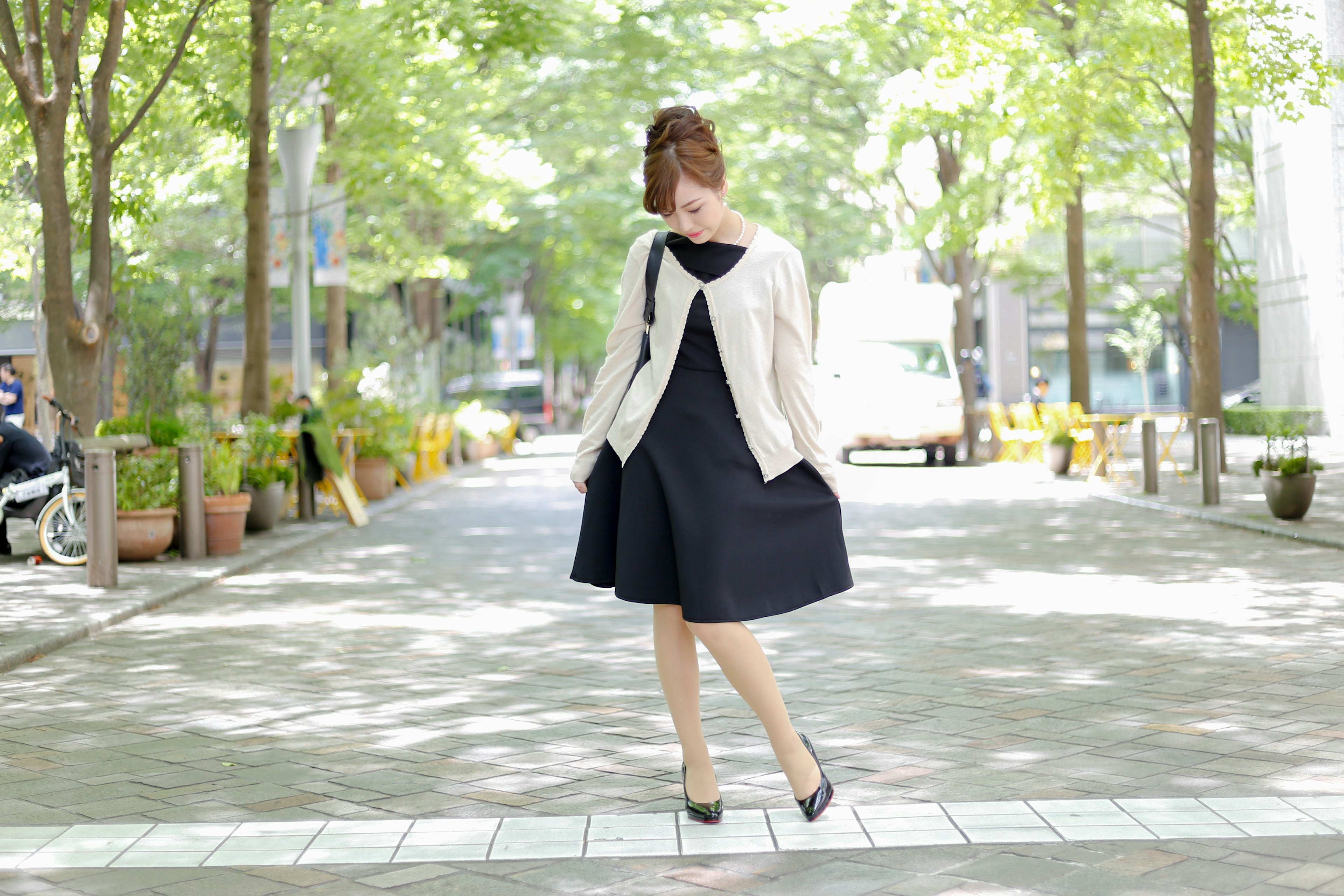 A woman in a black dress walking in a park setting