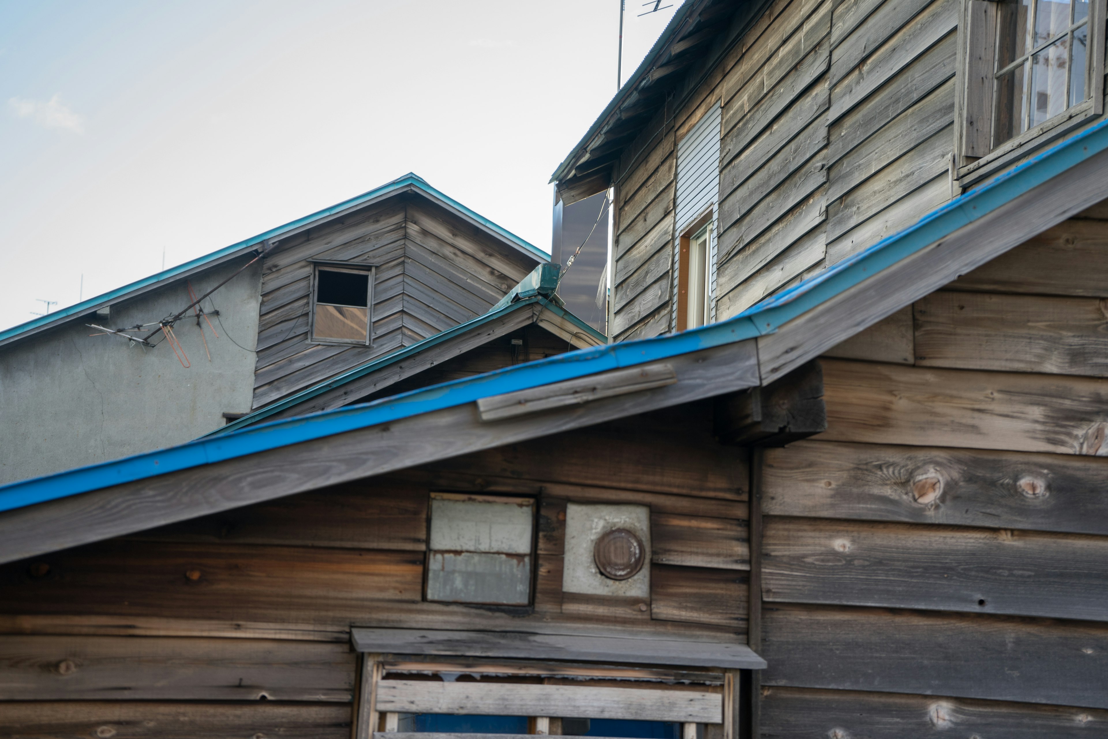 Vue de maisons en bois avec toits bleus montrant la texture et les détails des fenêtres