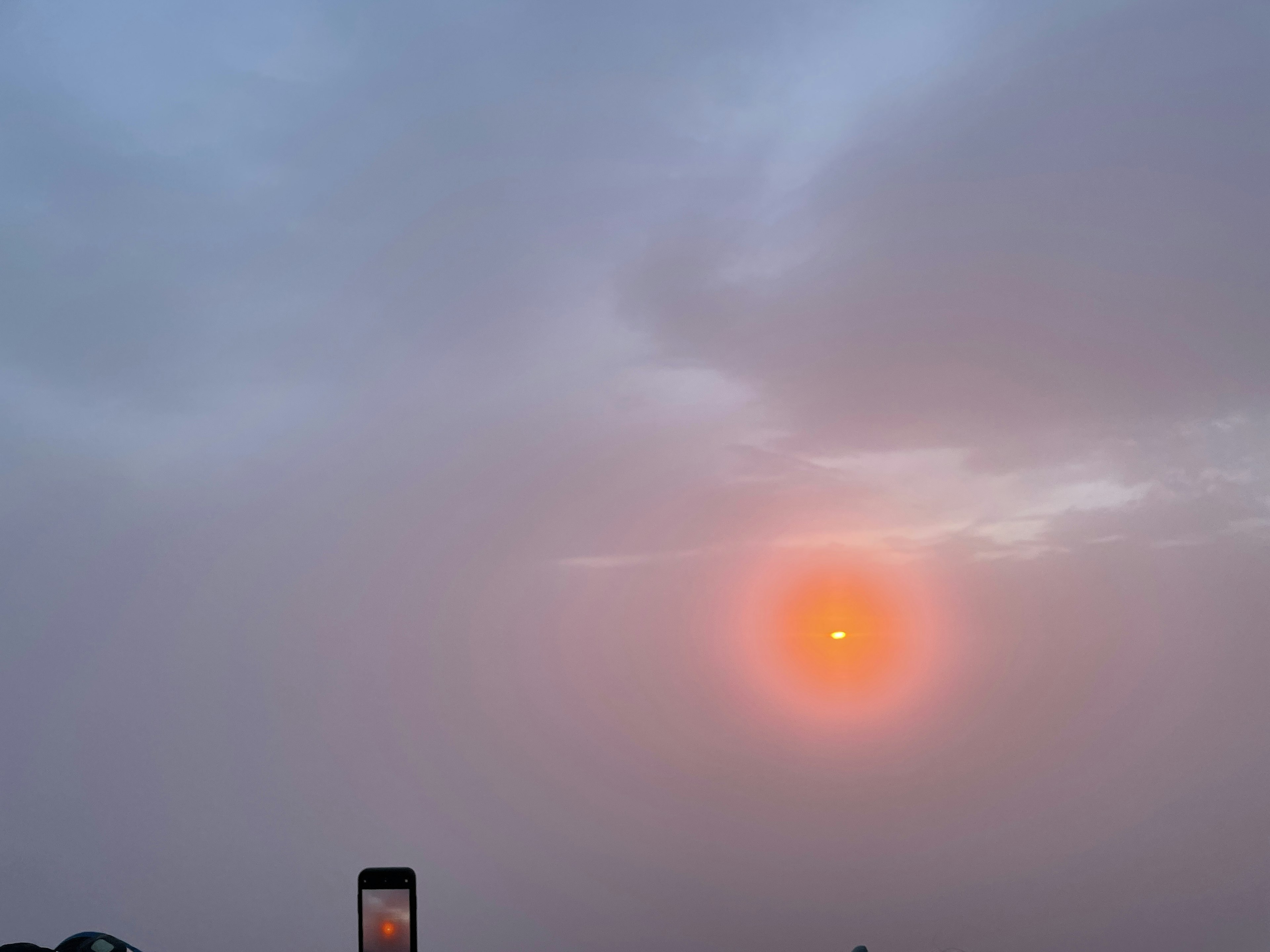 Una escena con un sol naranja brillando a través de un cielo nublado