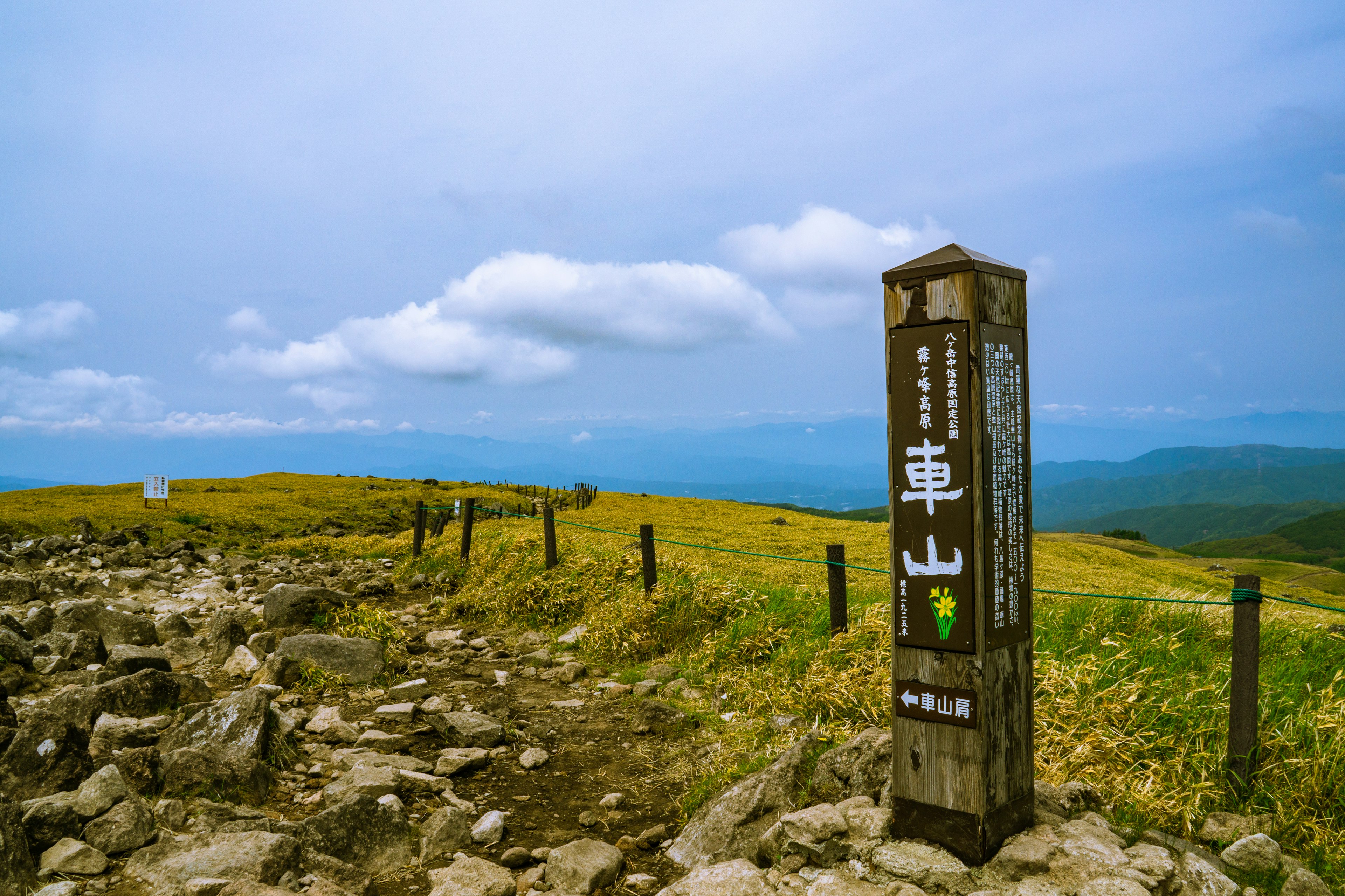 Wegweiser für Kusayama mit weiten Graslandschaften