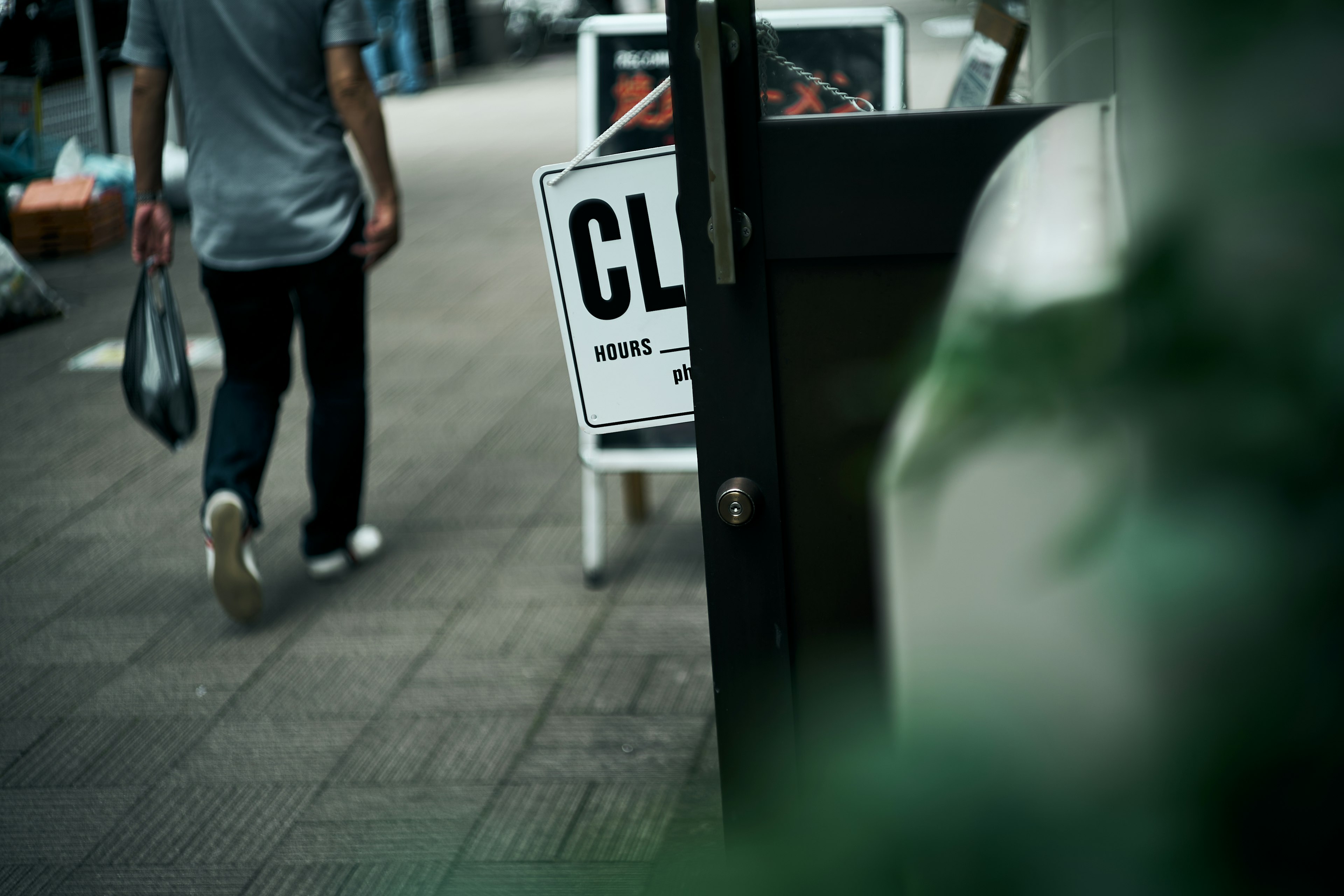 人が歩いている通りの風景と「CLOSED」と書かれた看板