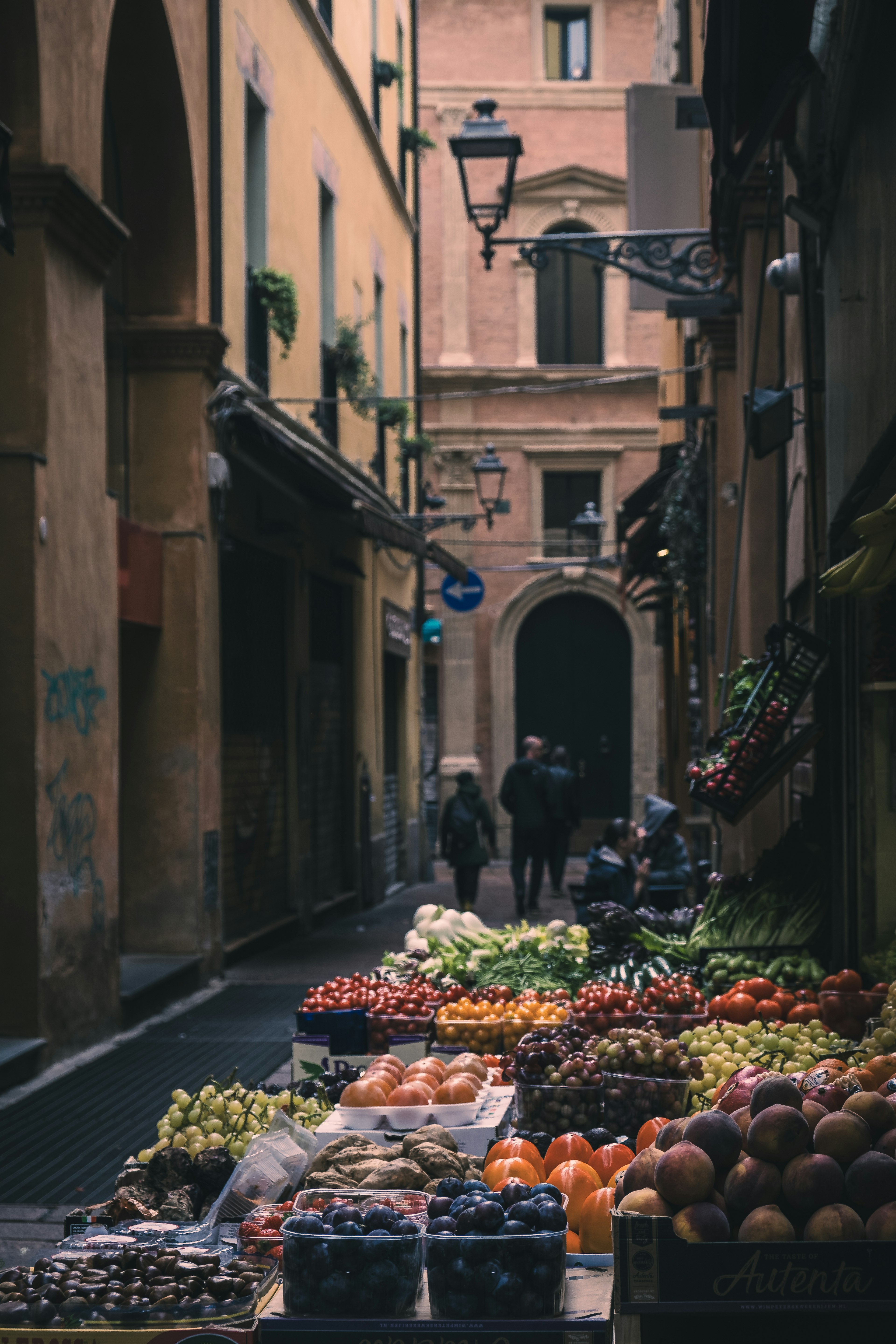 Narrow alley market with fresh fruits and people walking