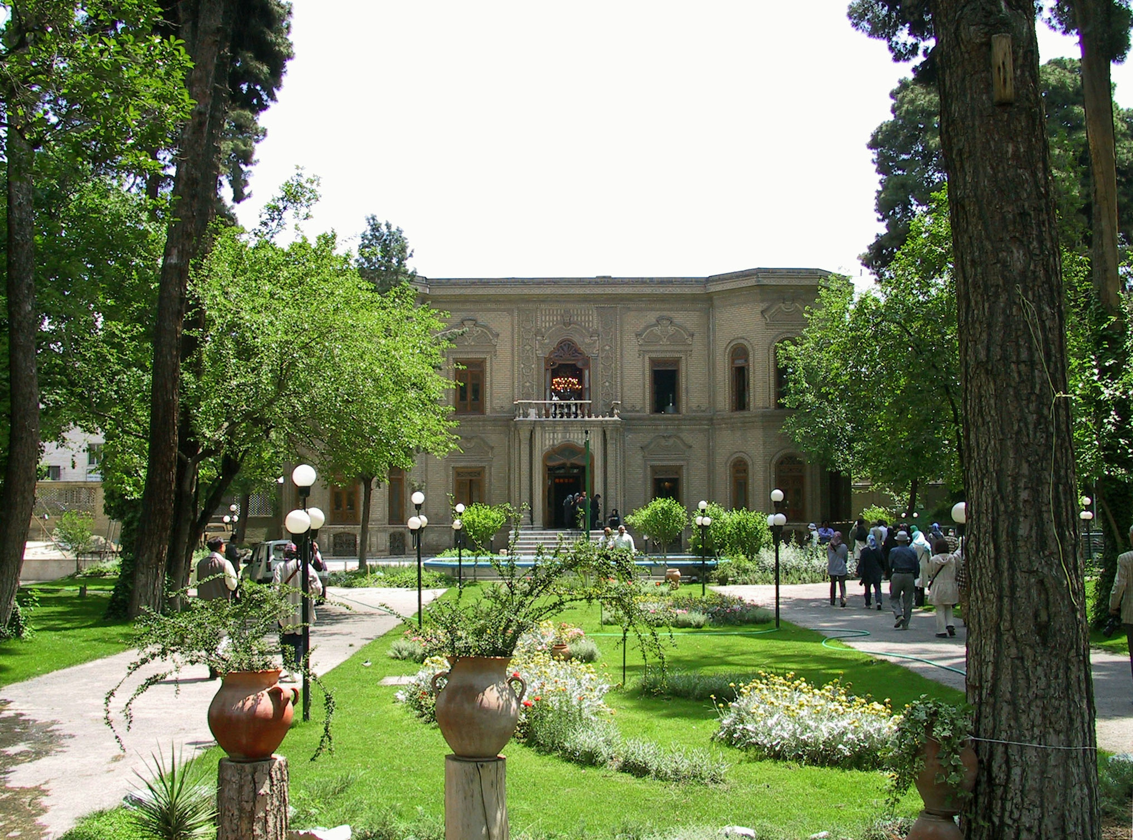 Blick auf ein historisches Gebäude, umgeben von einem üppigen Garten mit Bäumen und Blumen