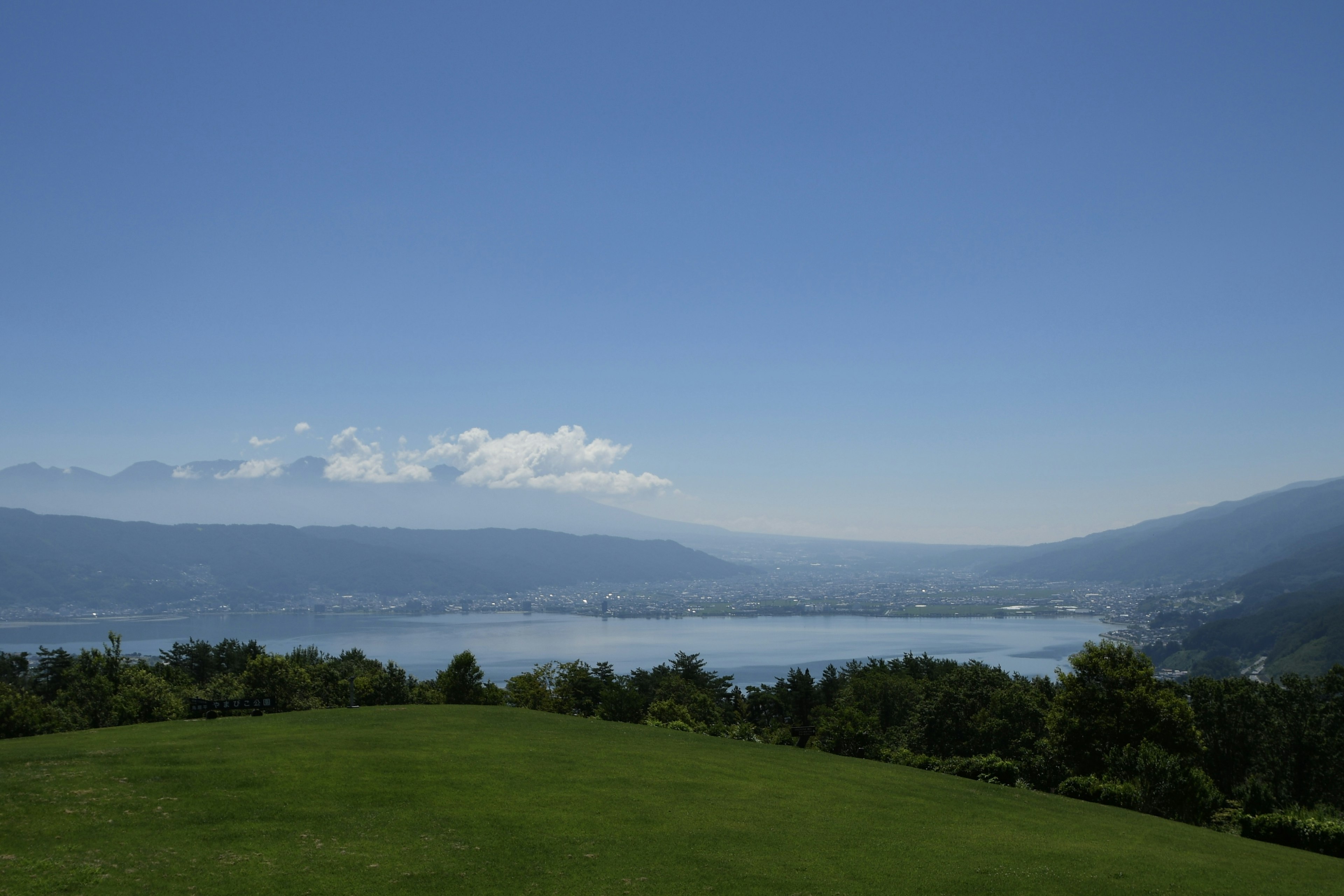 青空と湖の美しい風景 緑の草原と山々の遠景