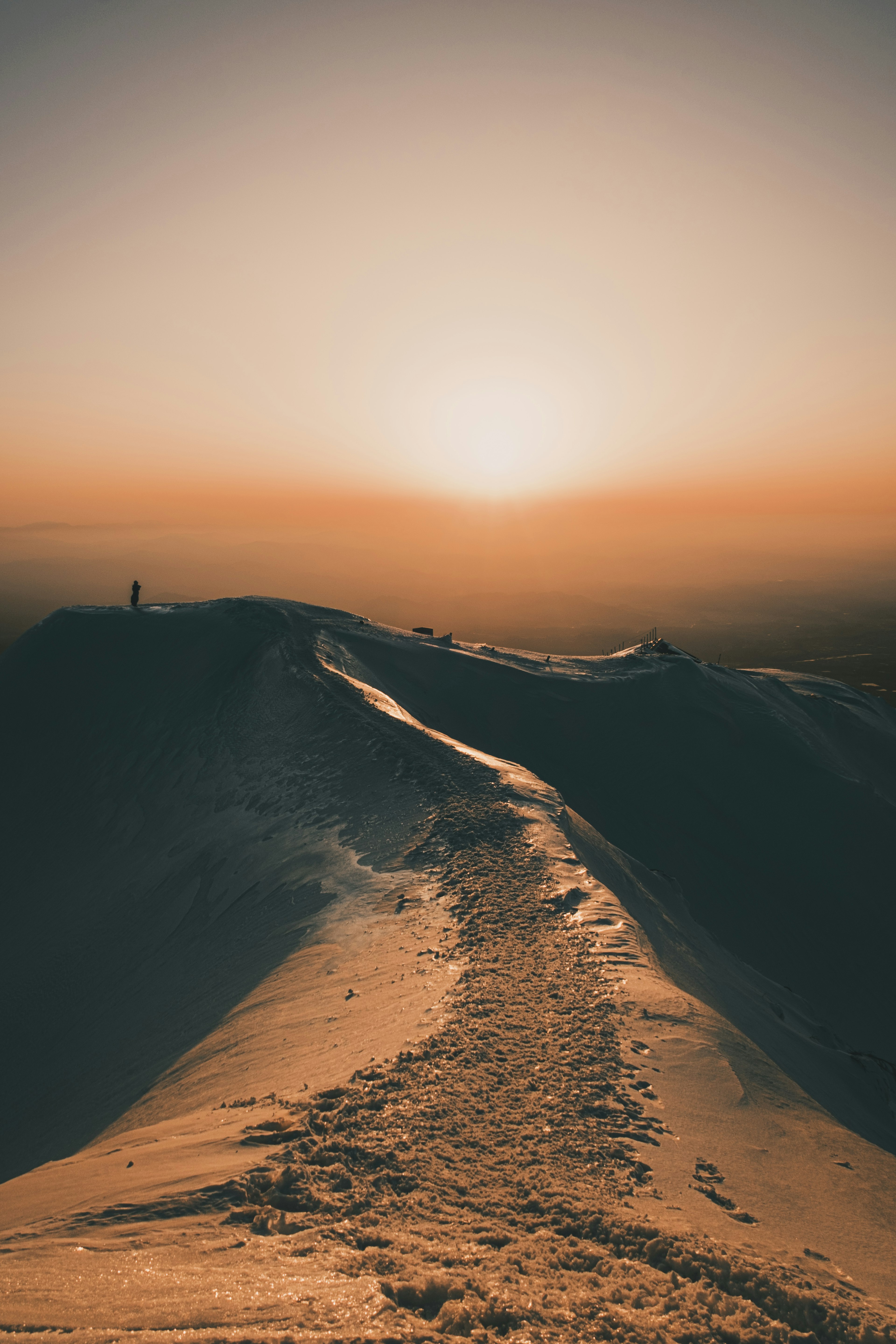 Cima de montaña cubierta de nieve con un amanecer de fondo