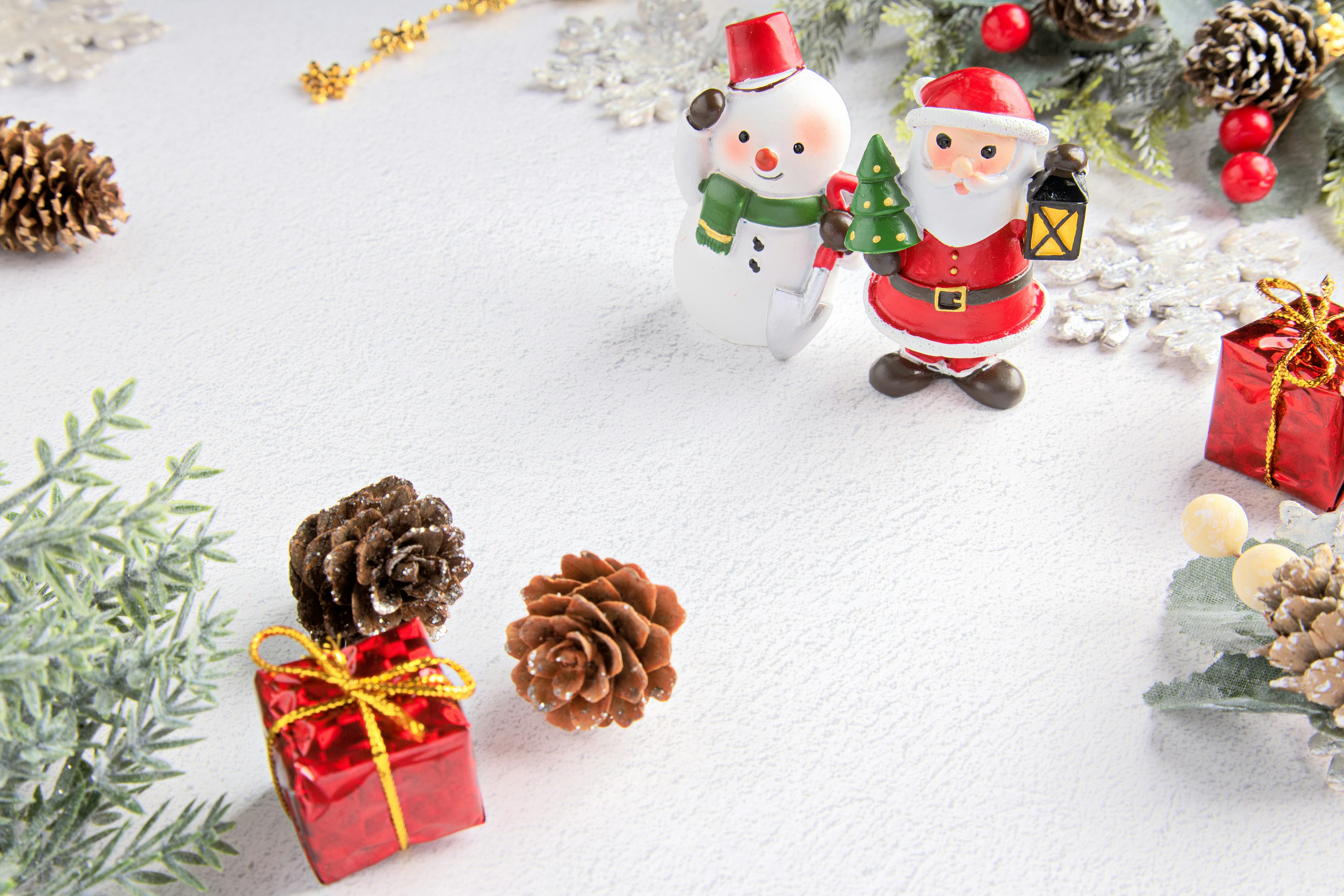 Figure di Babbo Natale e pupazzo di neve su un tavolo di Natale decorato con scatole regalo rosse e pigne