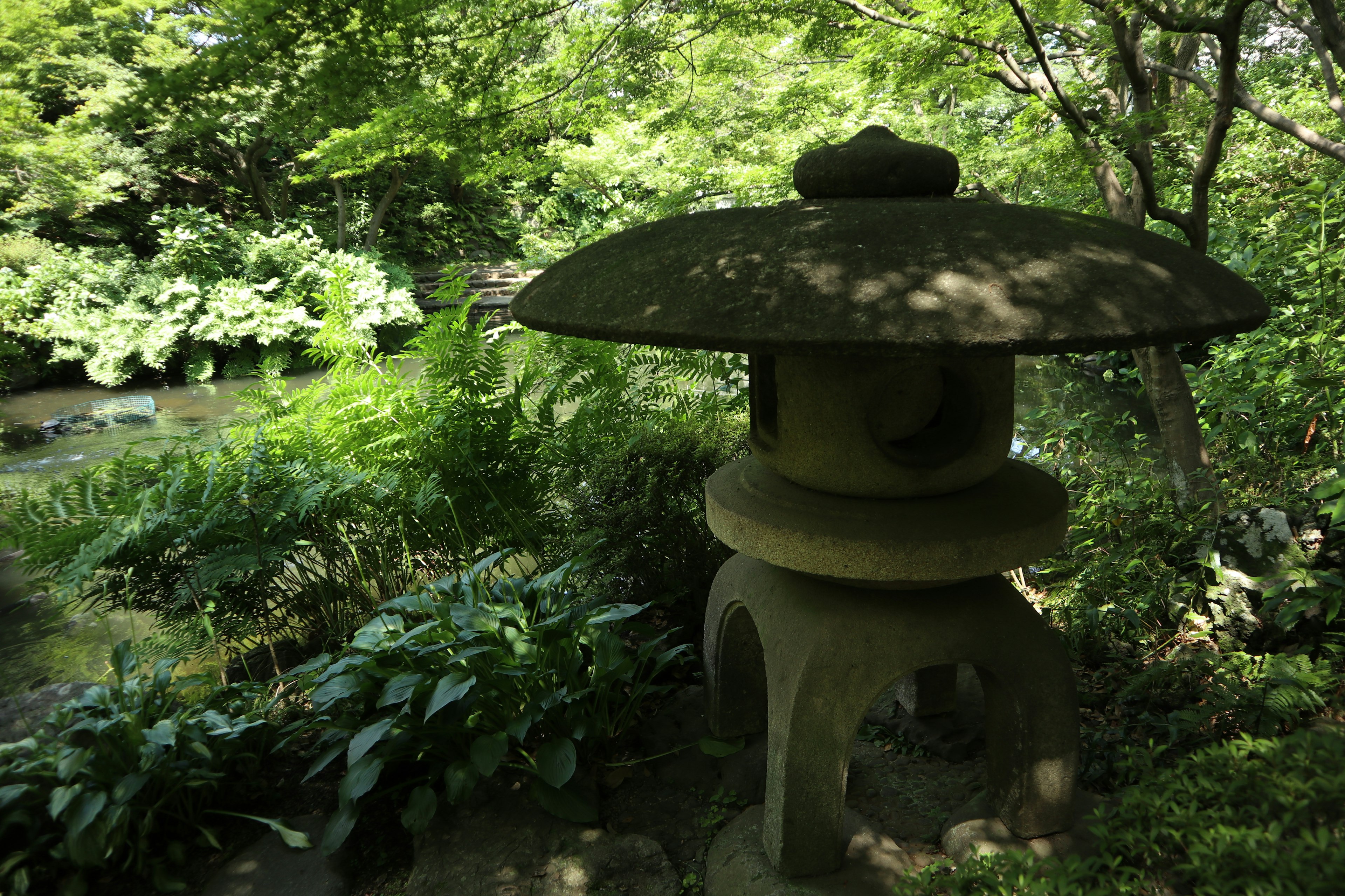 Lanterna di pietra in un tranquillo giardino giapponese circondato da verde lussureggiante