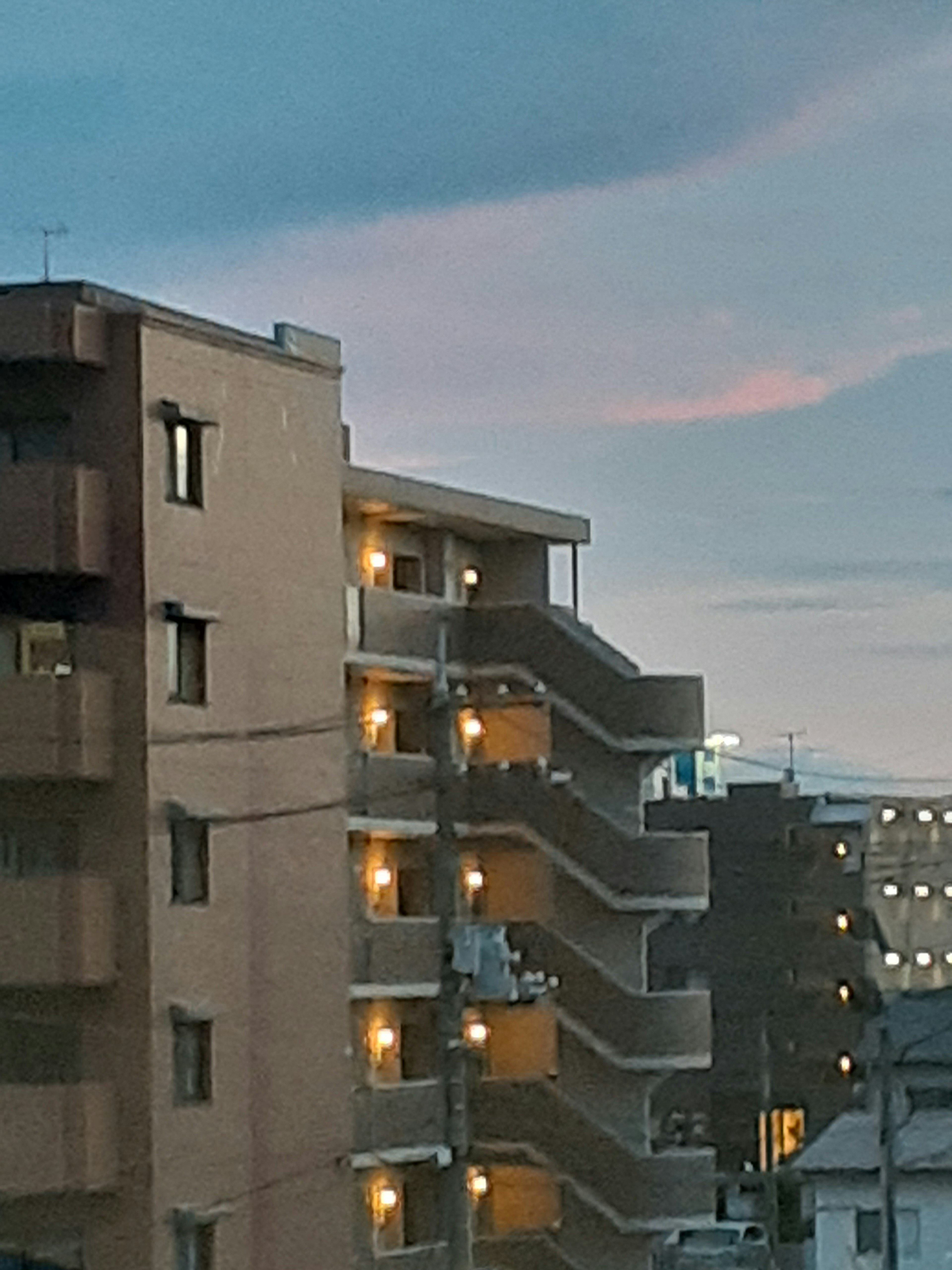 Vista exterior de un edificio de apartamentos al atardecer con una escalera